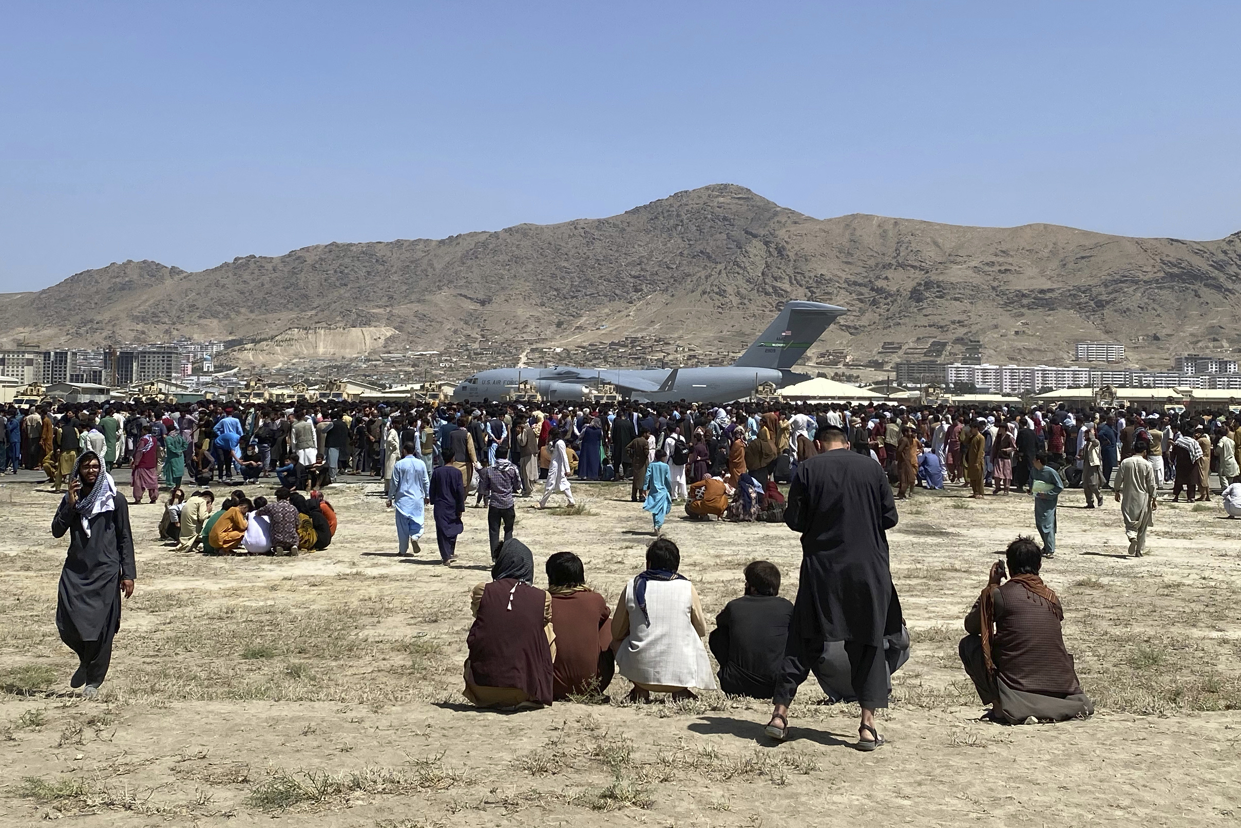 Hundreds of people gather around a US Air Force C-17 transport plane at the perimeter of the international airport in Kabul, Afghanistan on August 16, 2021 [Shekib Rahmani/AP]