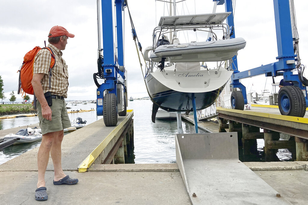 Robin Berthet watches as his sailboat is hauled out of the water onto dry land in advance of an expected storm in Plymouth, Massachusetts