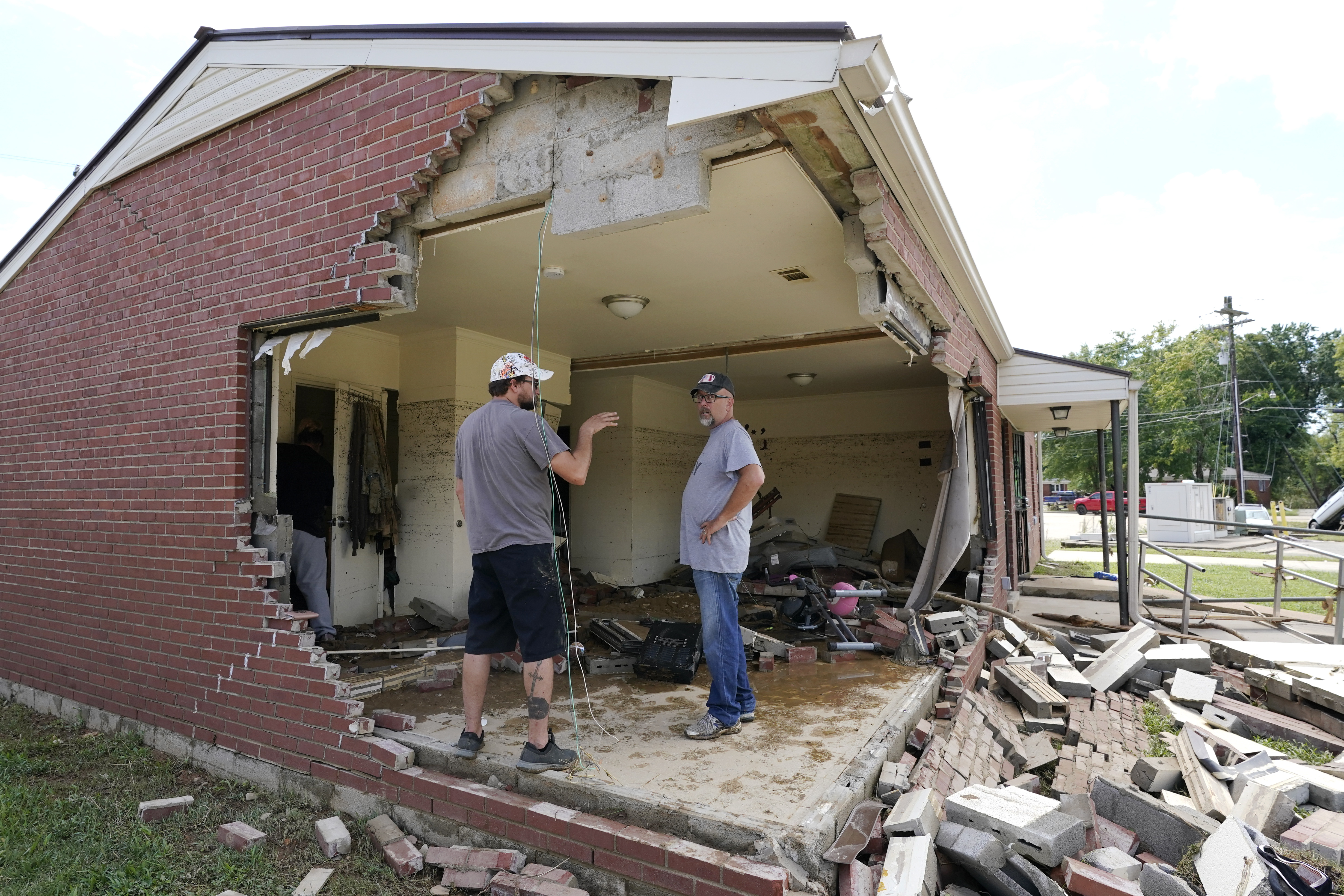 Brian Mitchell, right, looks through the damaged home of his mother-in-law along with family friend Chris Hoover, left, Sunday, August 22, 2021, in Waverly, Tennessee