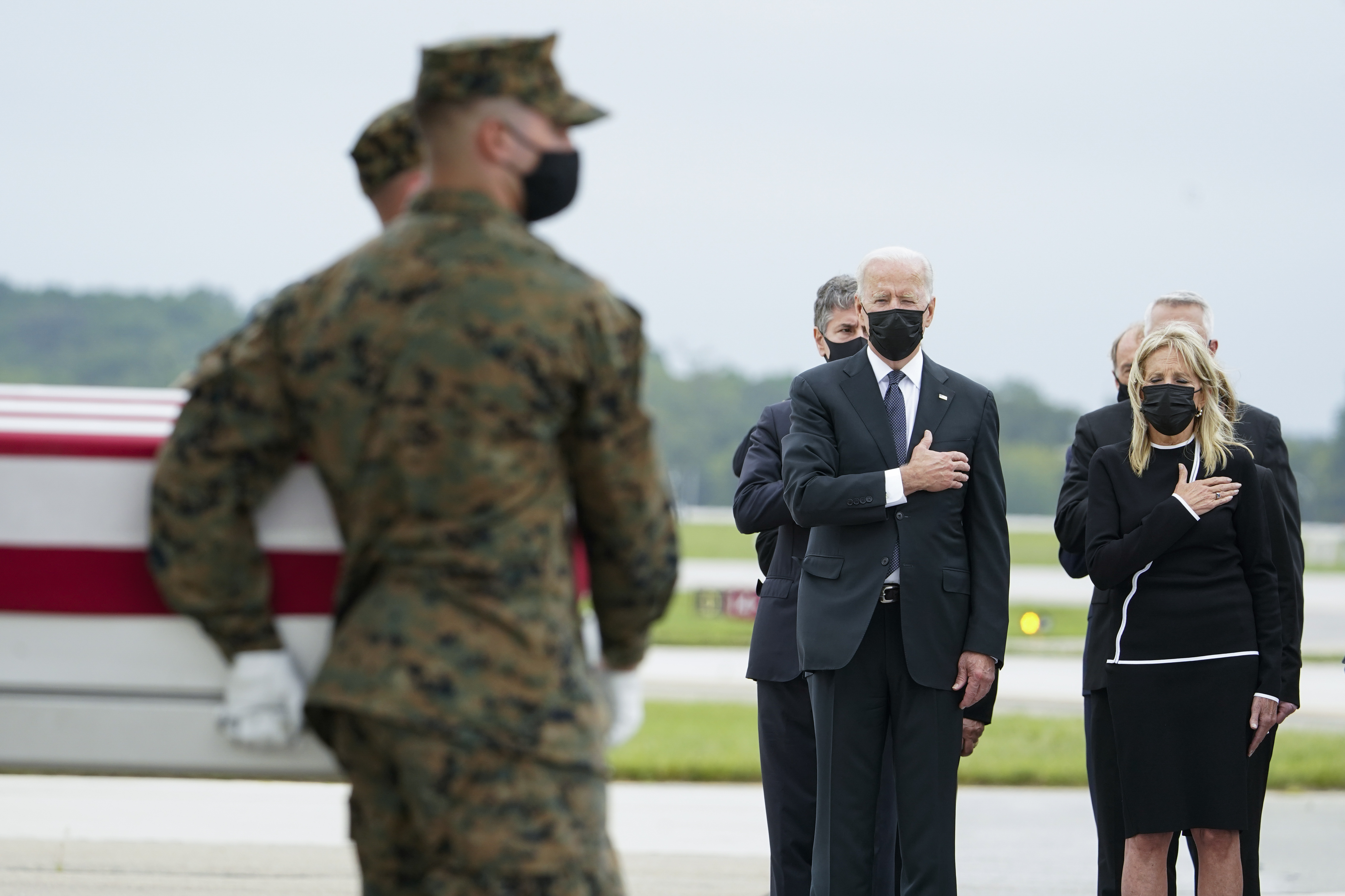 President Joe Biden and first lady Jill Biden watch as a Marine Corps carry team moves a transfer case containing the remains of a Marine Corps Sgt. at Dover Air Force Base, Delaware