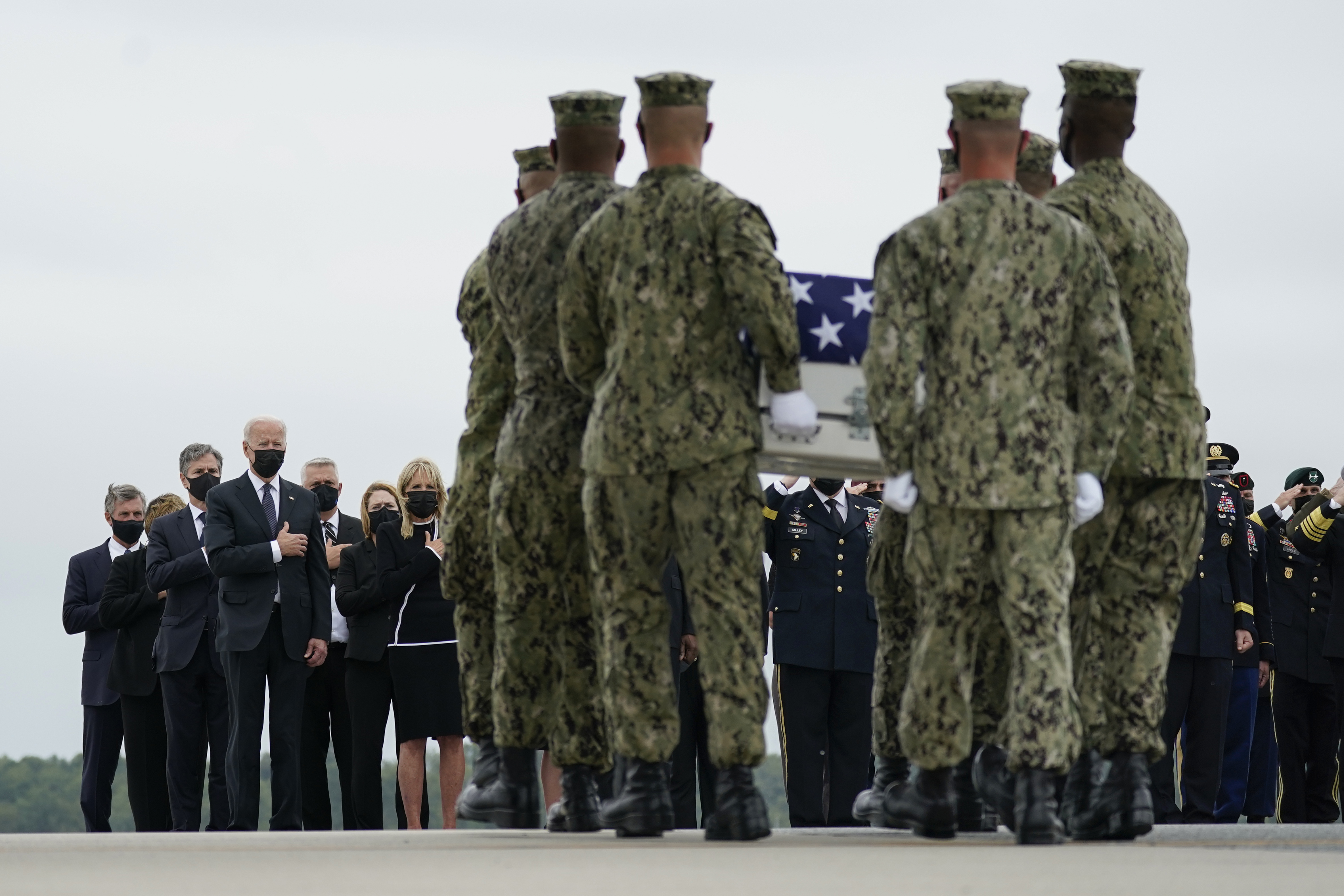 President Joe Biden, first lady Jill Biden, Secretary of State Antony Blinken and others look on as a team moves a case with the remains of Navy Corpsman Maxton W. Soviak, 22, during a ceremony at Dover Air Force Base