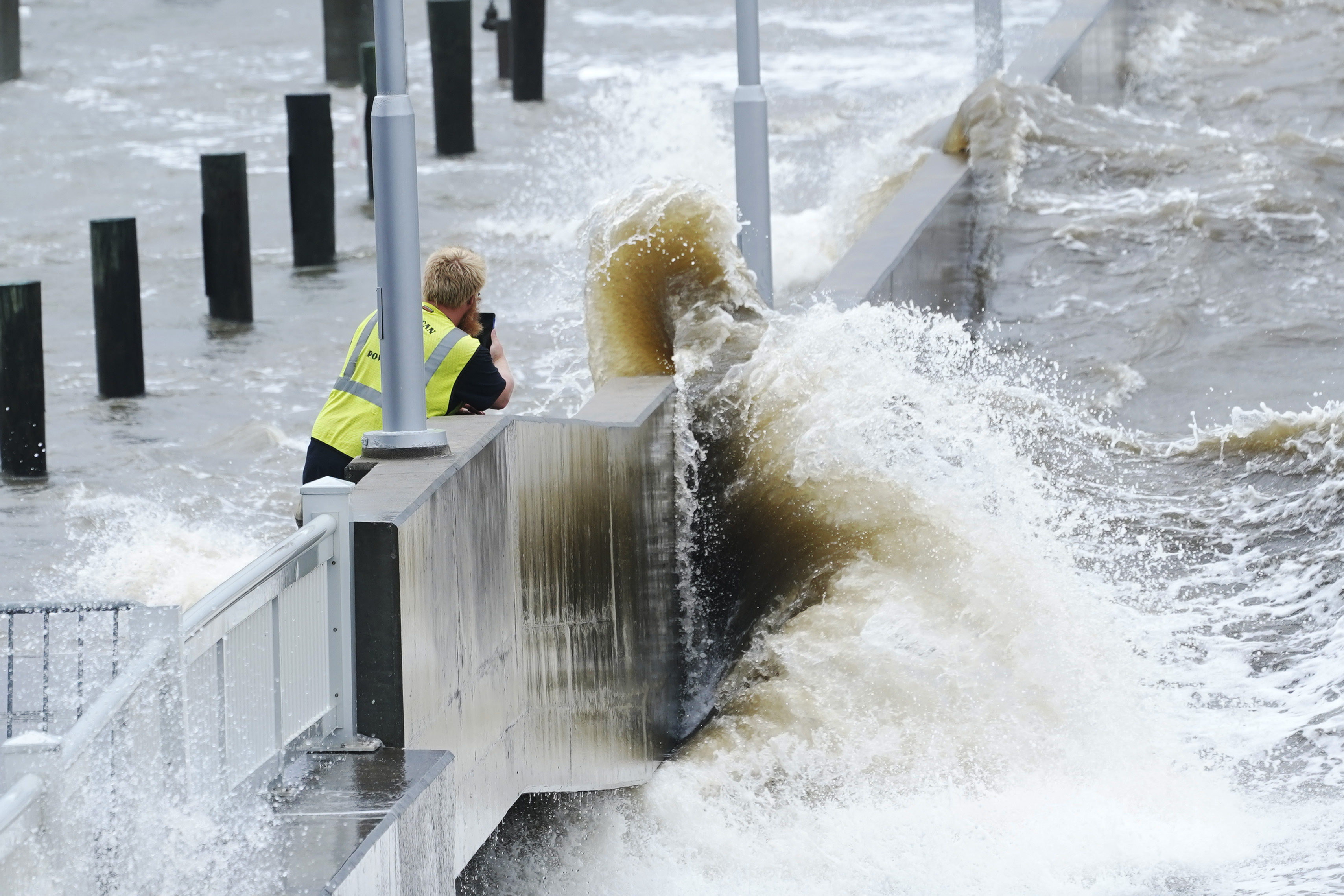 A utility worker photographs waves slamming against a sea wall at the marina as outer bands of Ida arrive, August 29, Bay Saint Louis, Mississippi