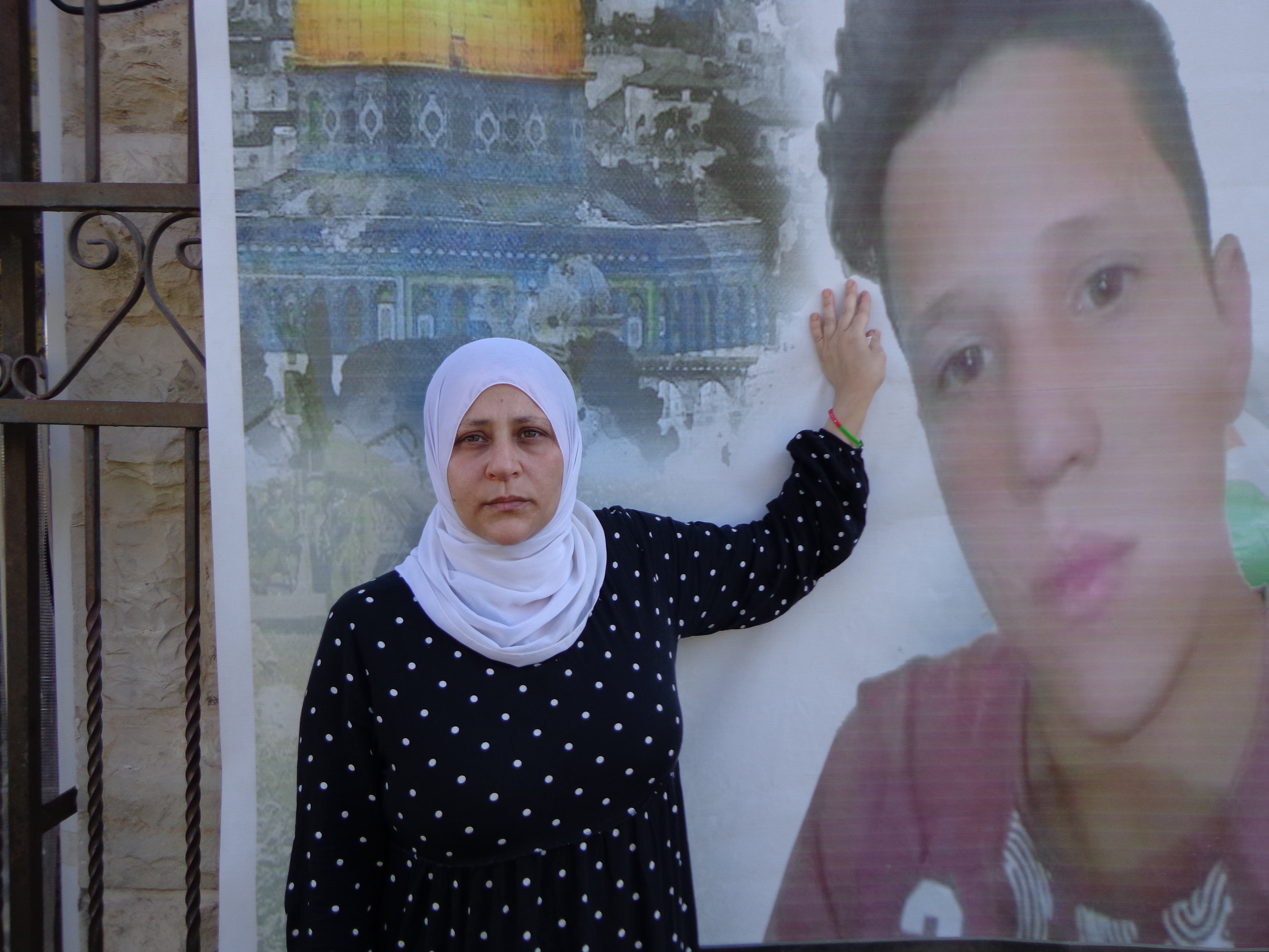 Bara’a Tamimi stands by a poster of her son, Muhammad, who was shot and killed by Israeli forces [Al Jazeera]