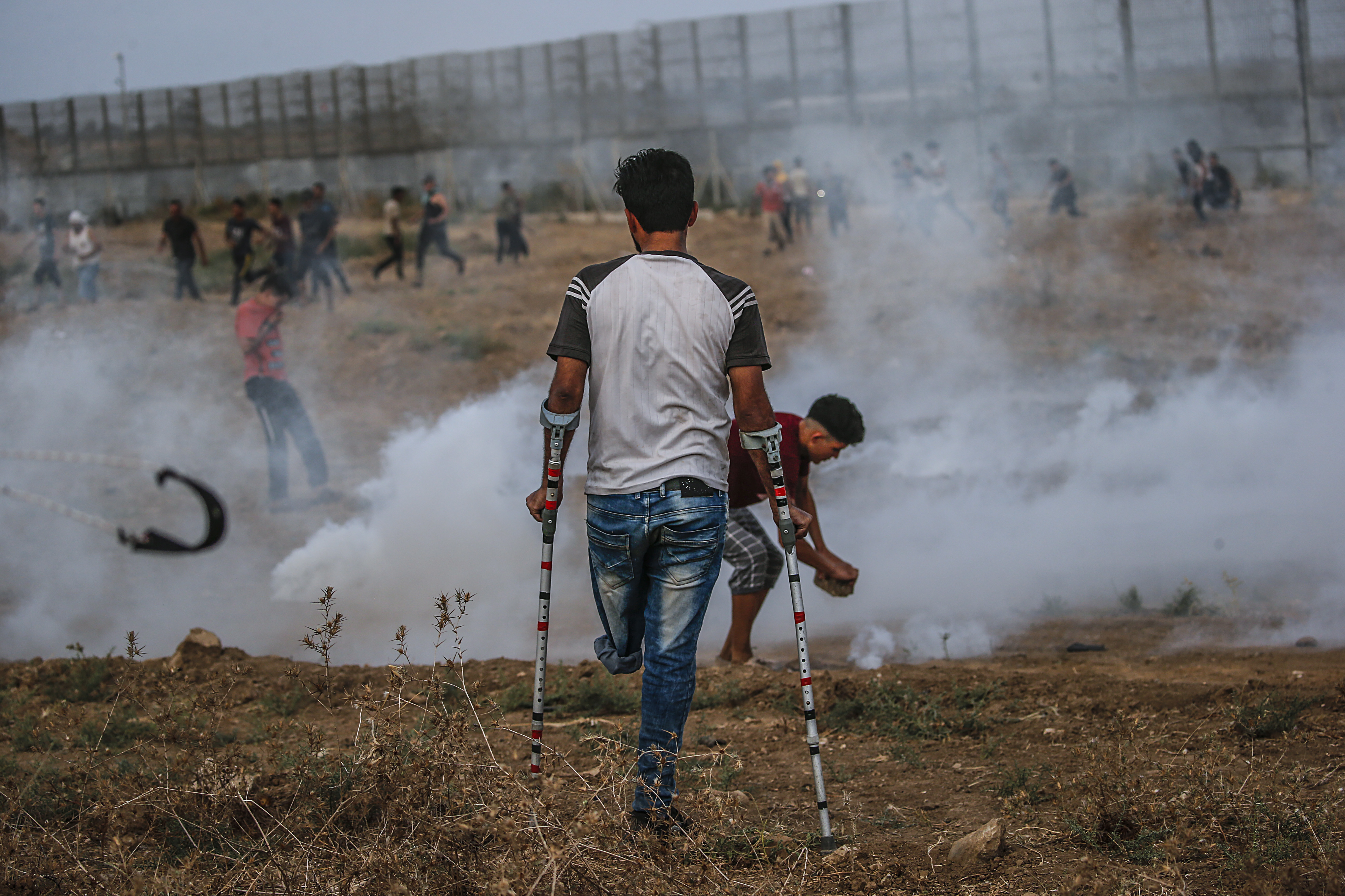 Palestinian protesters take cover from Israeli tear gas near the separation fence