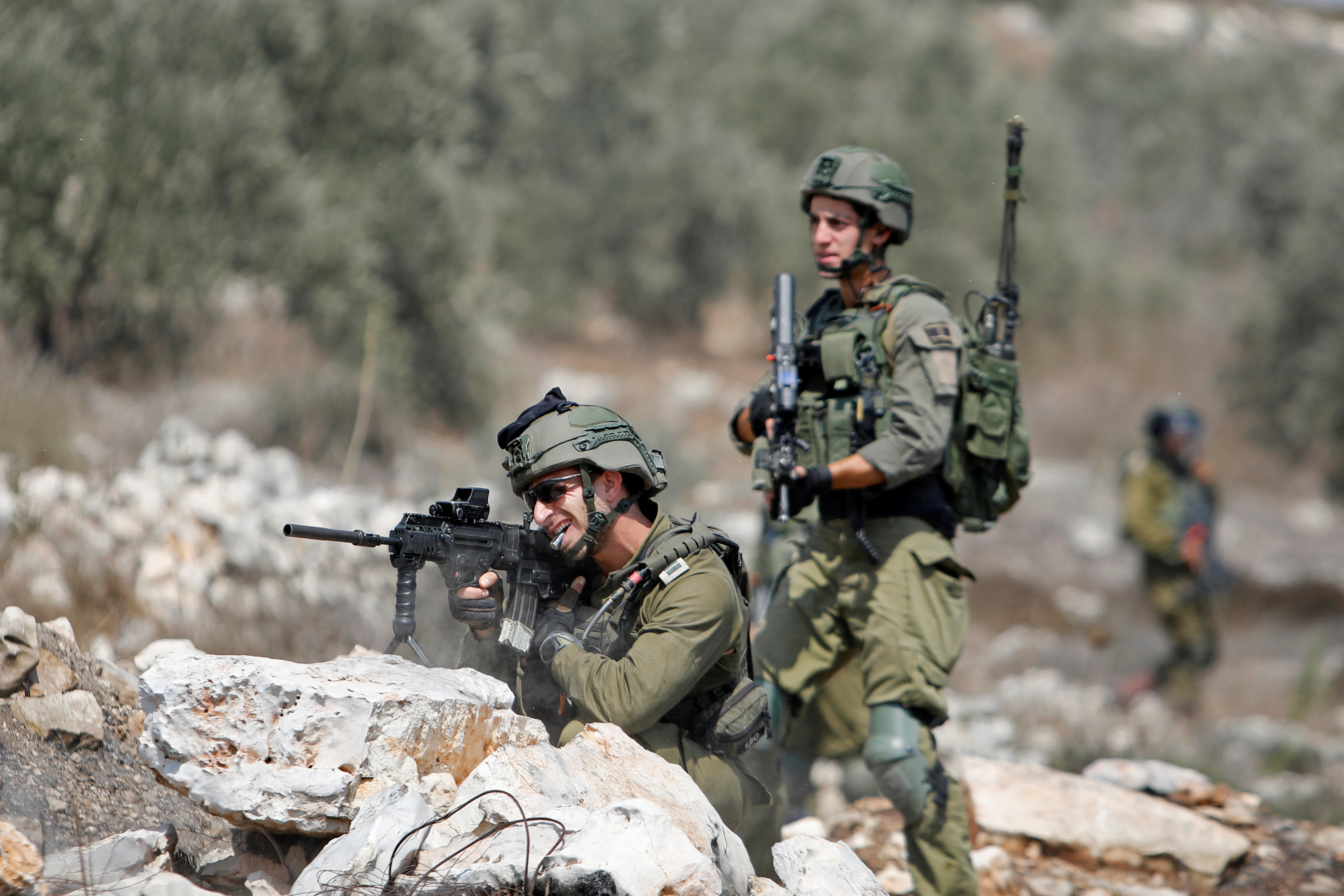 An Israeli soldier points his weapon towards Palestinian demonstrators