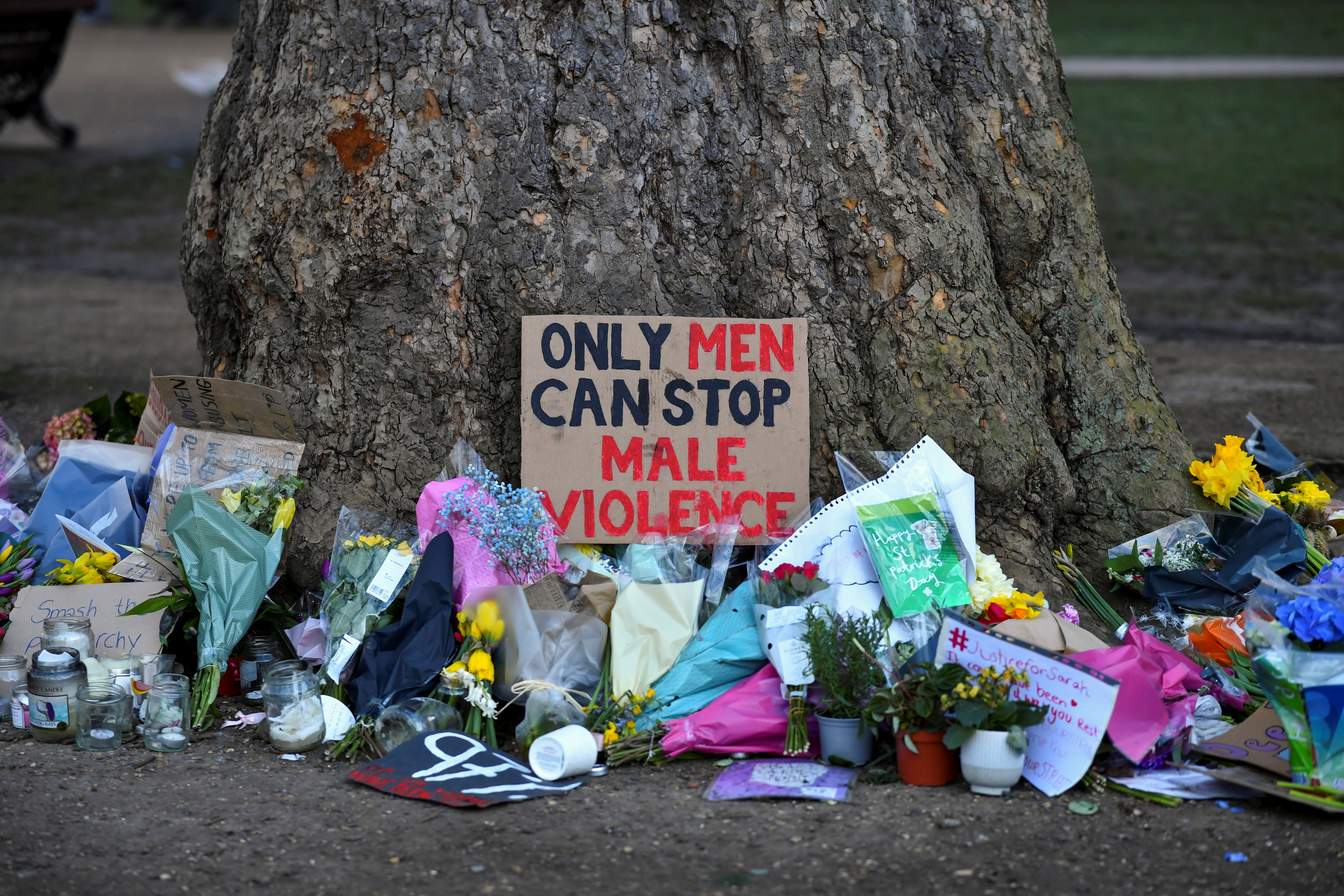 Signs and flowers are left under a tree near the Clapham Common bandstand following the kidnap and murder of Sarah Everard [File: Dylan Martinez/Reuters]