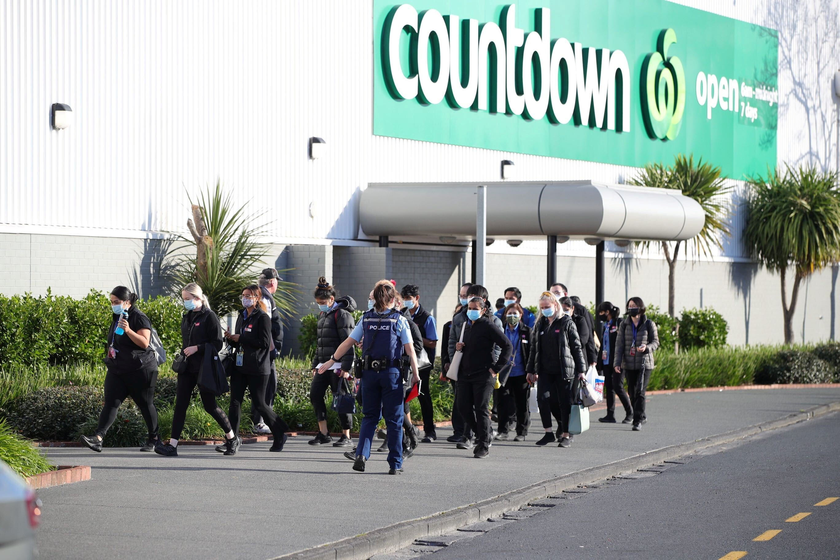 A police officer leads employees of a nearby store away from the scene of an attack carried out by a man who injured multiple people at a shopping mall in Auckland, New Zealand, September 3, 2021