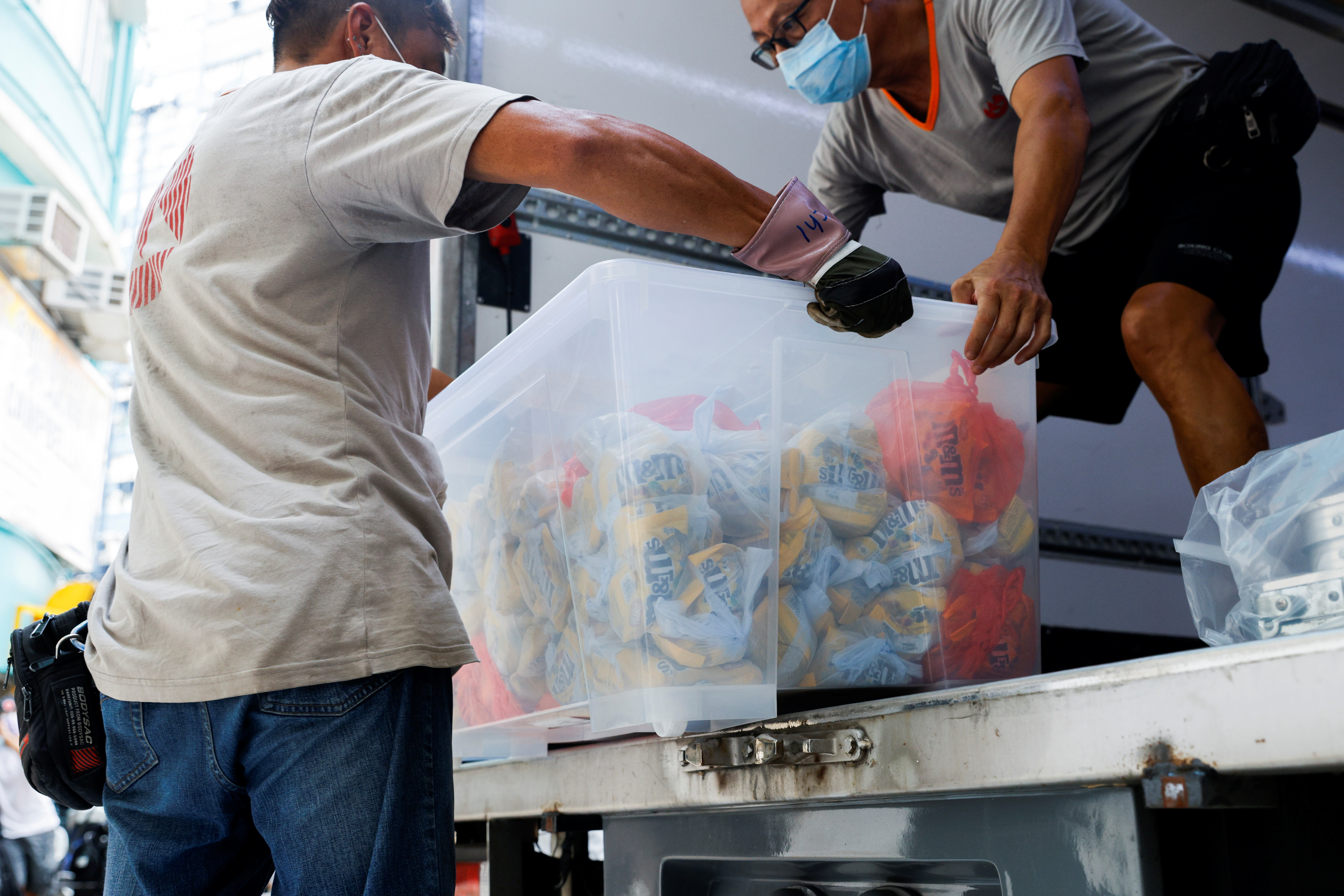 A mover collects a box full of M&M’s chocolates that were seized by police after they searched a warehouse used by Student Politicism, in Hong Kong