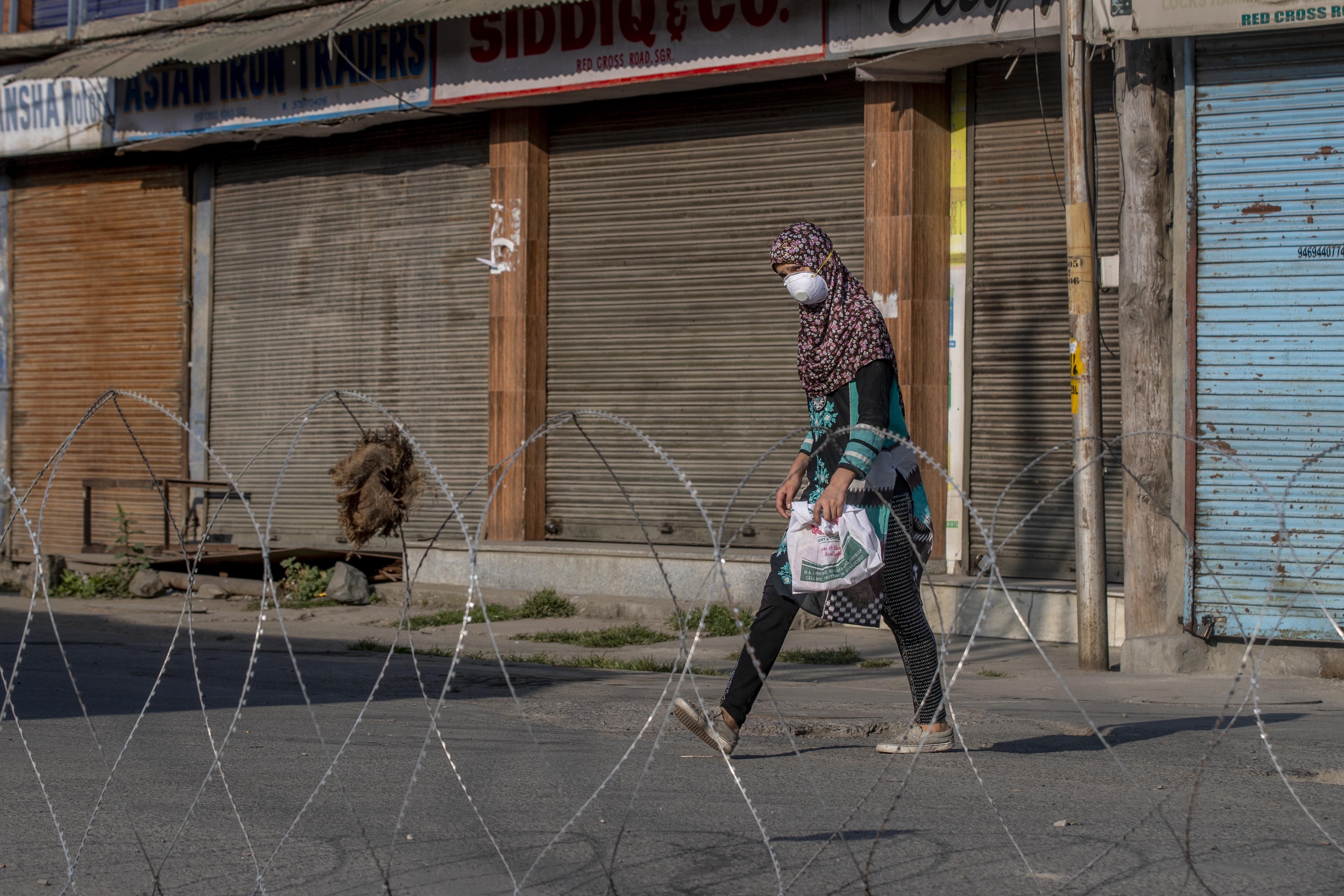 A Kashmiri girl walks past a barbed-wire road blockade in the main city of Srinagar