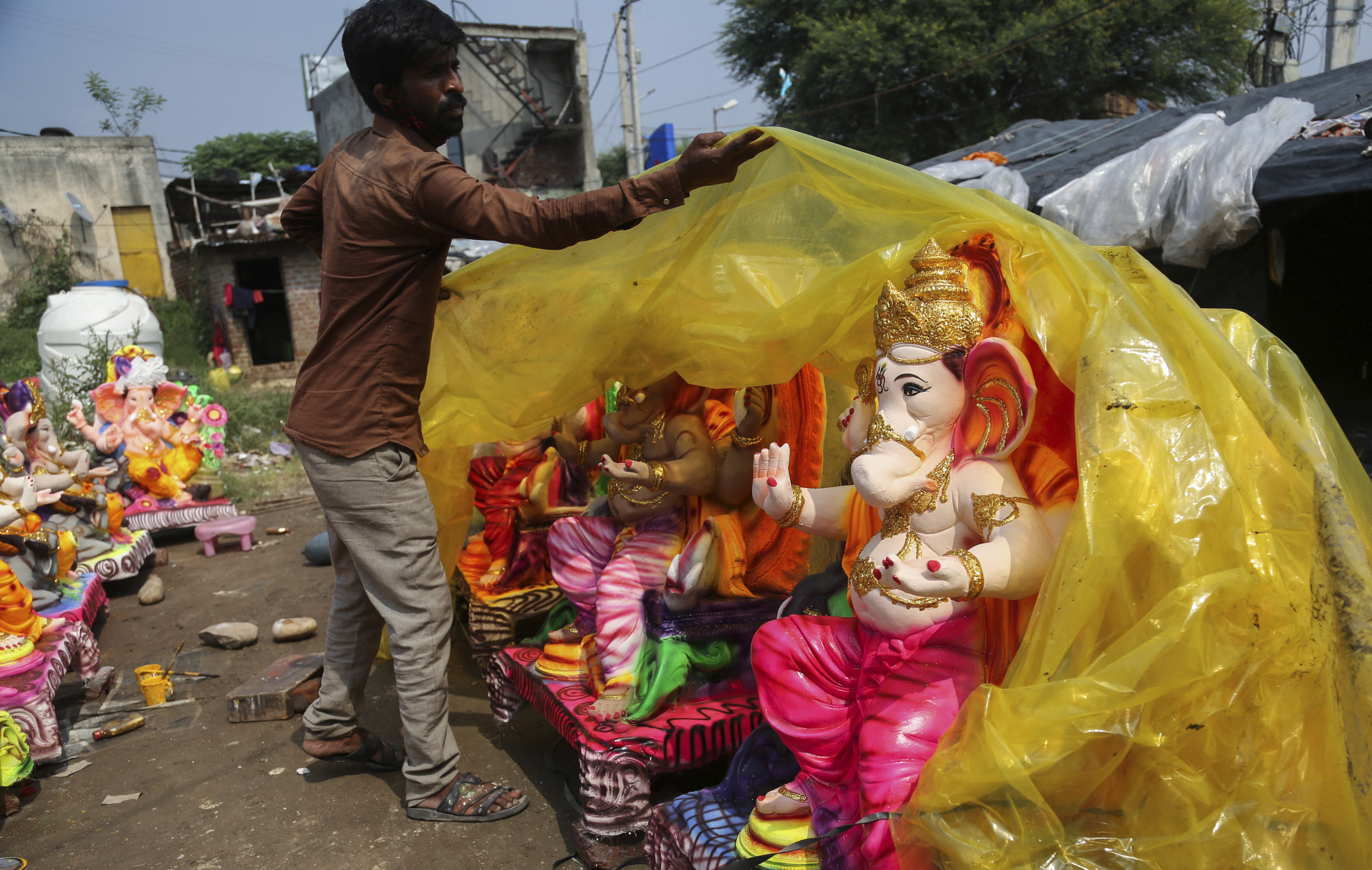 A worker covers a Ganesha idol for sale for the upcoming Ganesh Chaturthi festival, in Jammu, Indian-administered Kashmir