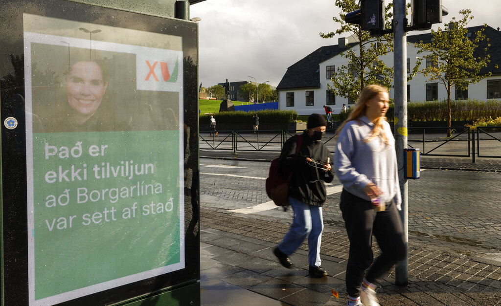 People walk past an election poster from the Left-Green Movement showing Prime Minister Katrin Jakobsdottir