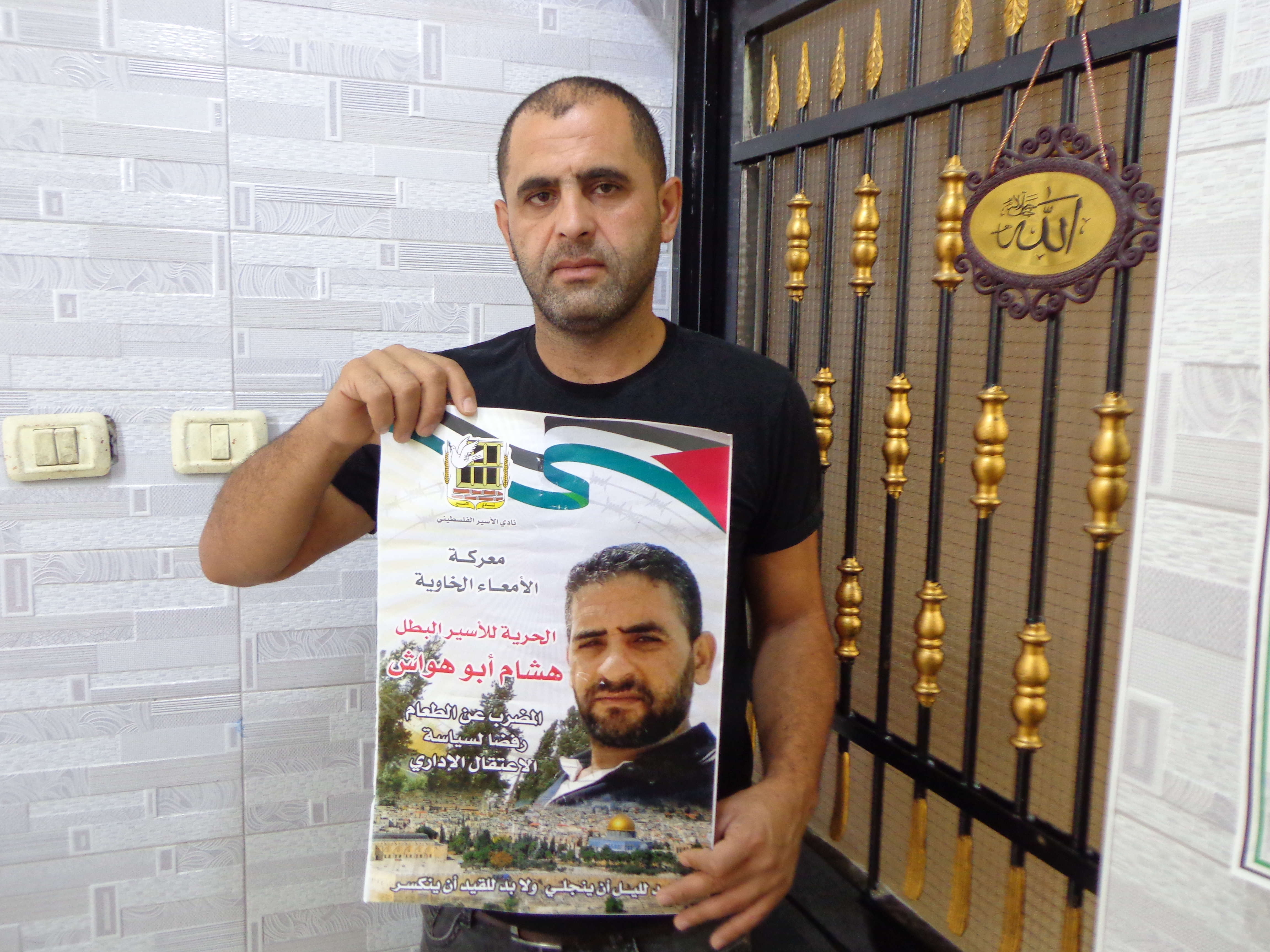 Emad Abu Hawash holds a poster of his brother [Al Jazeera]