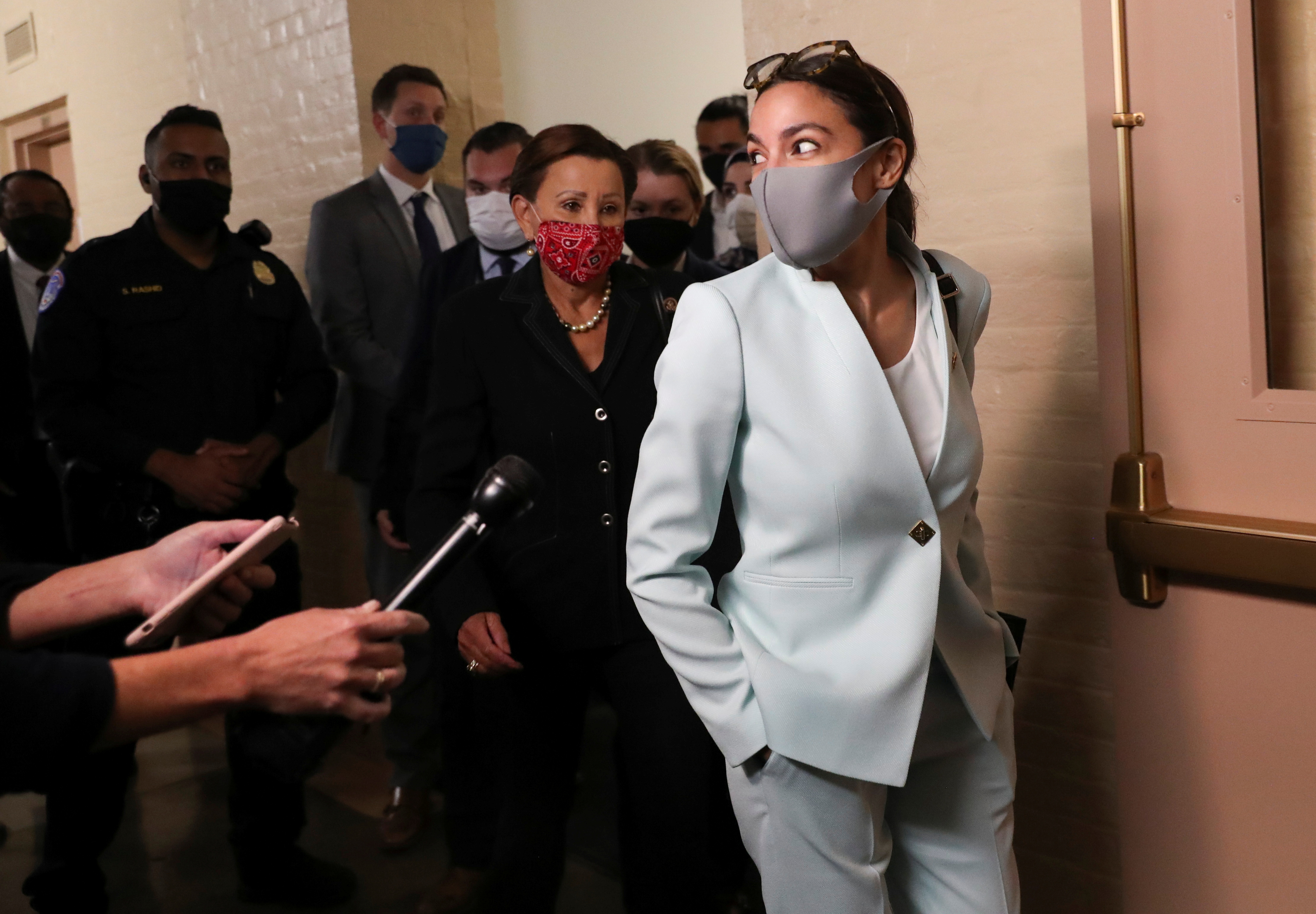 Progressive lawmaker Alexandria Ocasio-Cortez, right, listens to questions from reporters as she departs after a meeting between President Biden and Democratic lawmakers at the US Capitol that Speaker of the House Nancy Pelosi hosted to promote bipartisan infrastructure bill