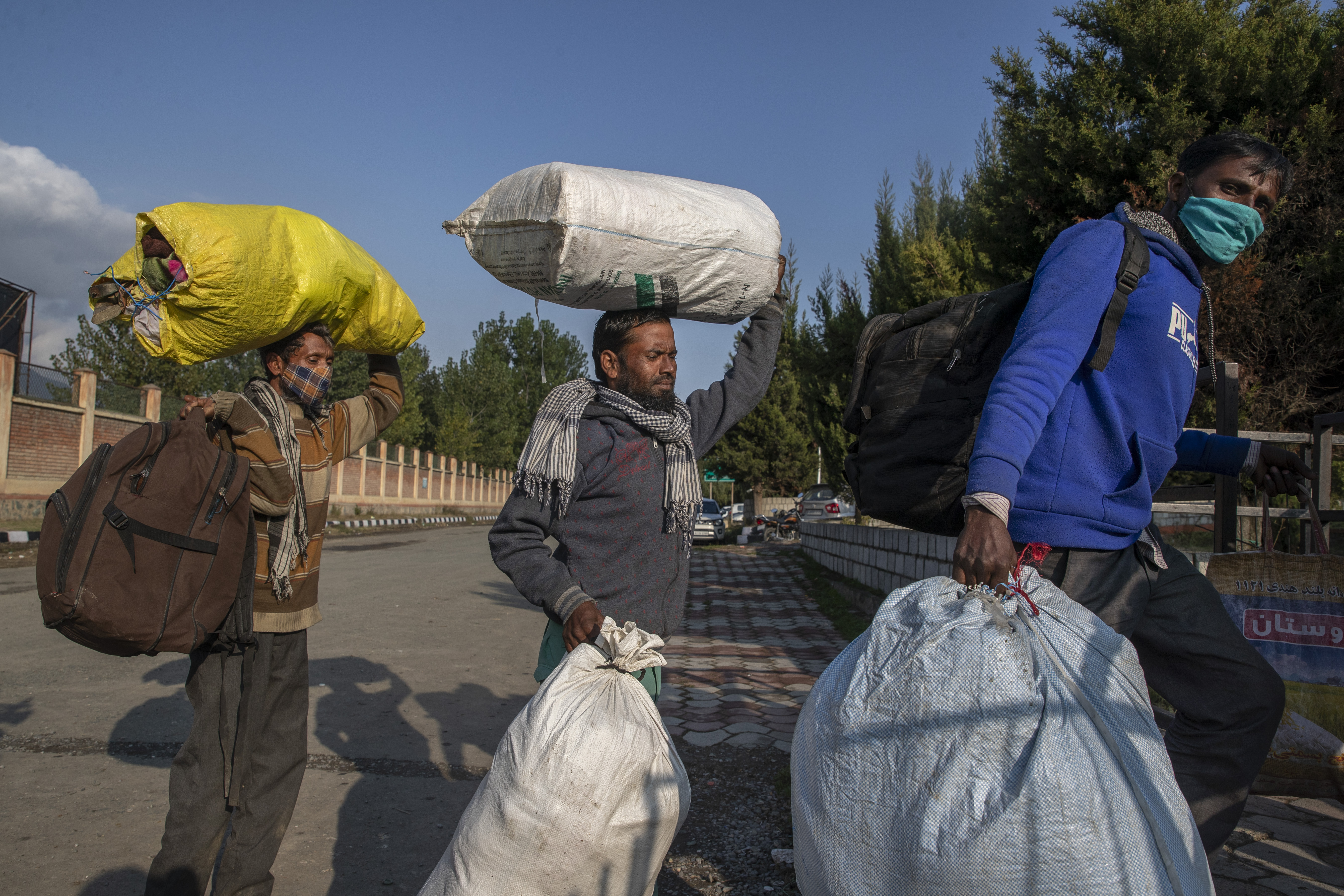 Indian migrant workers carrying their belongings walk towards a railway station on the outskirts of Srinagar as they leave for their home states