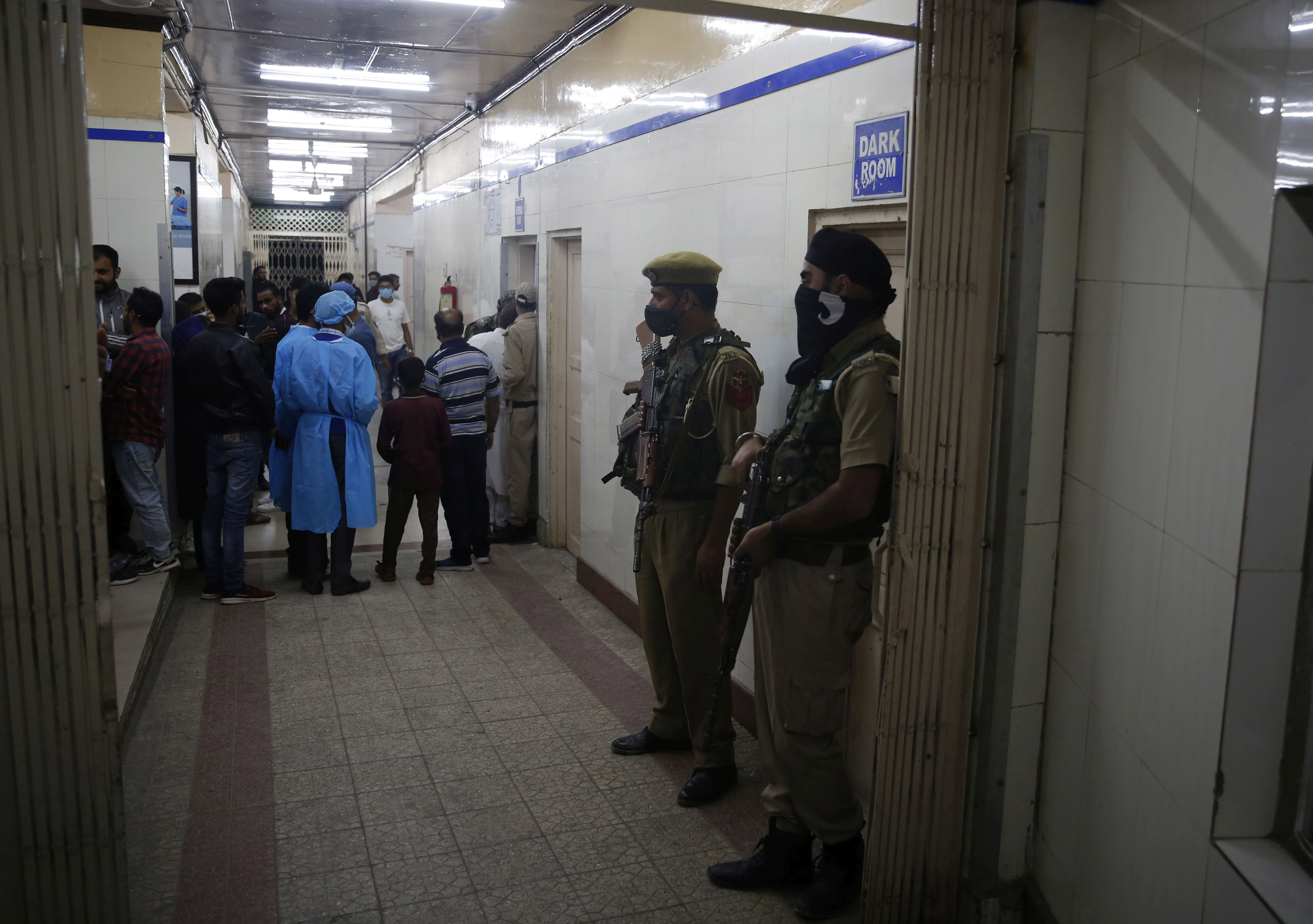Indian policemen stand guard inside a hospital in Srinagar where businessman Makhan Lal Bindroo was admitted after he was shot