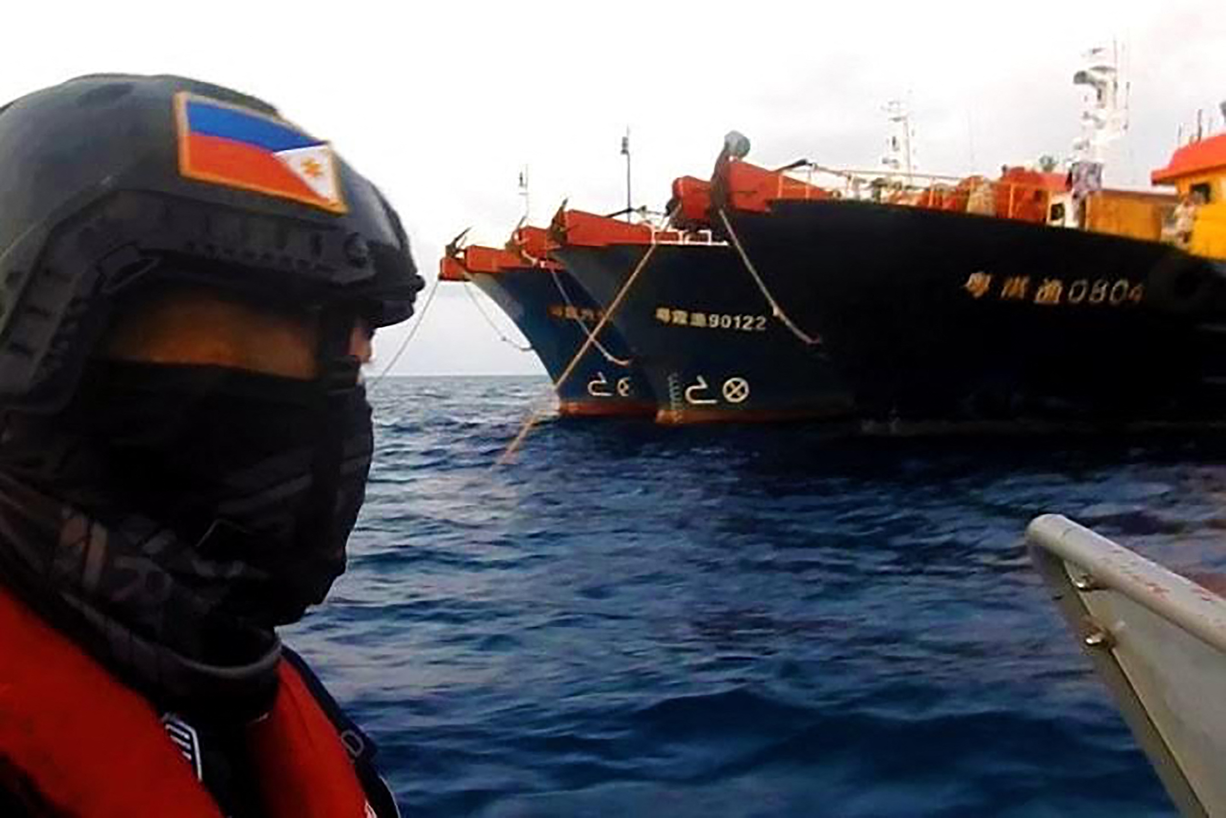 Philippine Coast Guard personnel on rubber dinghies patrol near Chinese vessels that massed at Whitsun Reef in the disputed Spratly Islands earlier this year [File: Philippine Coast Guard /AFP]