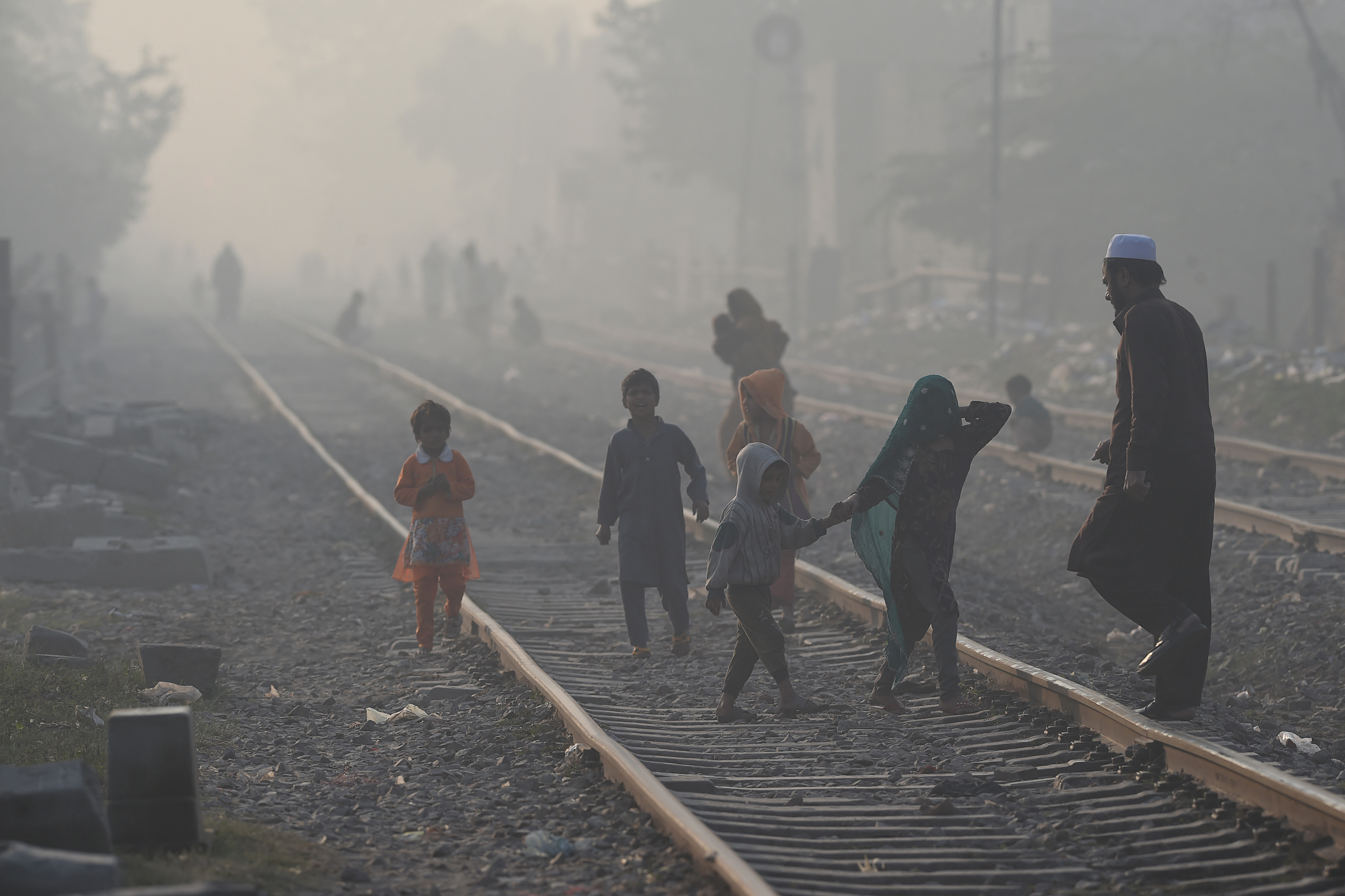 People walk on a railway track amid smoggy conditions in Lahore