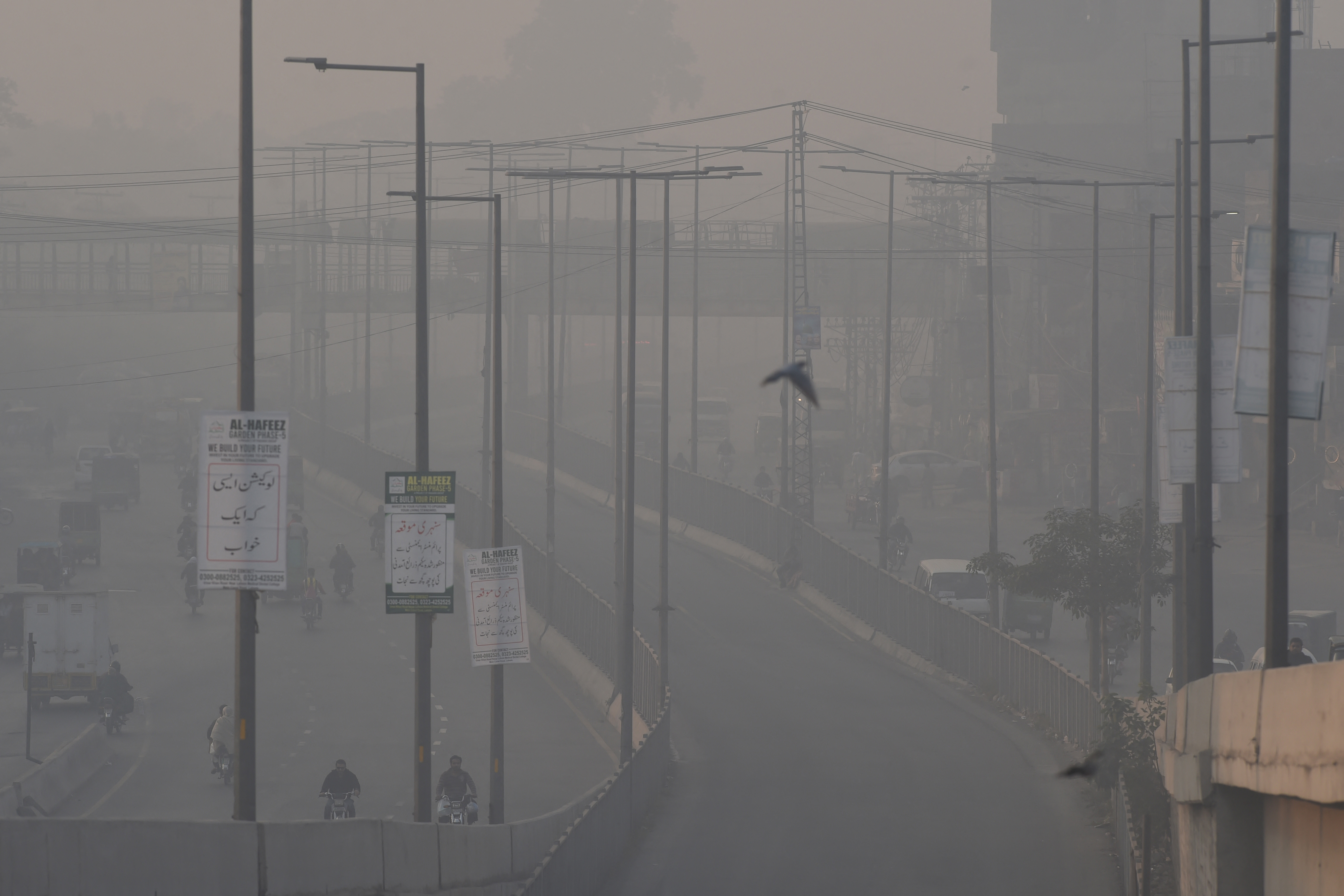 Commuters ride along a road amid smoggy conditions in Lahore