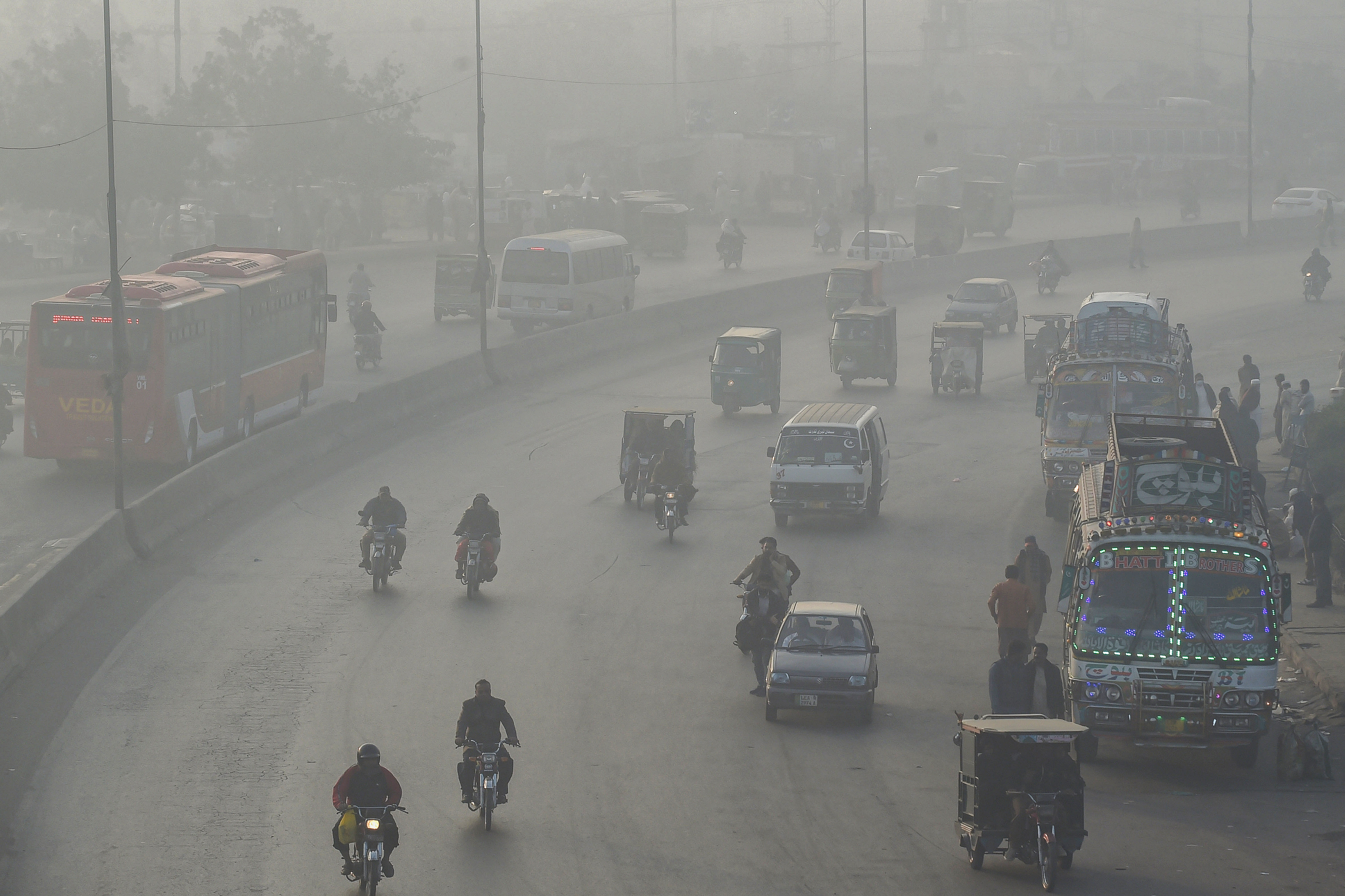Commuters make their way along a road amid smoggy conditions in Lahore