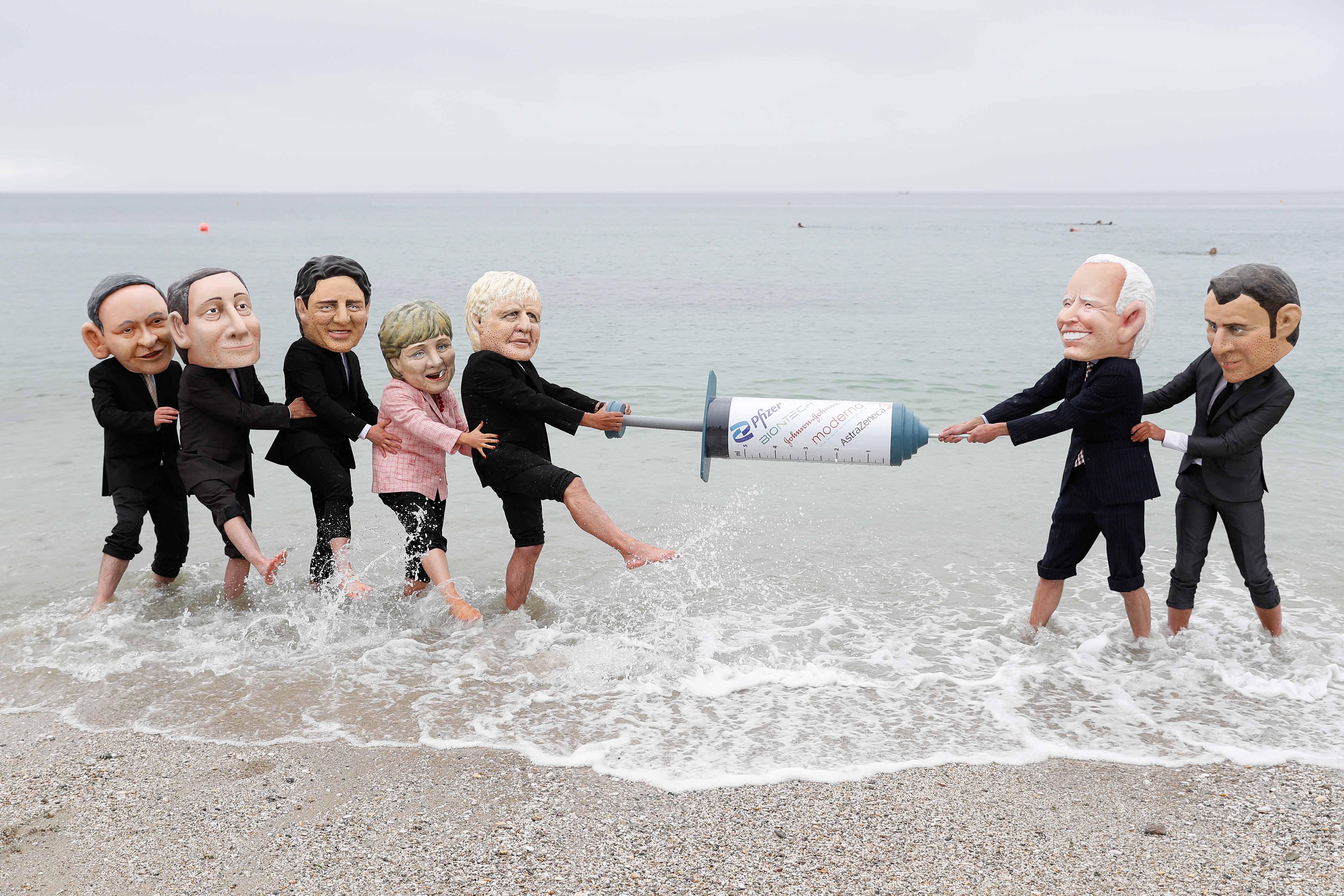 Oxfam activists with big head caricatures of G7 leaders pretend to fight over a COVID-19 vaccine during a protest on the sidelines of the G7 summit in Cornwall, Britain, on June 11, 2021 [File: Reuters/Peter Nicholls]