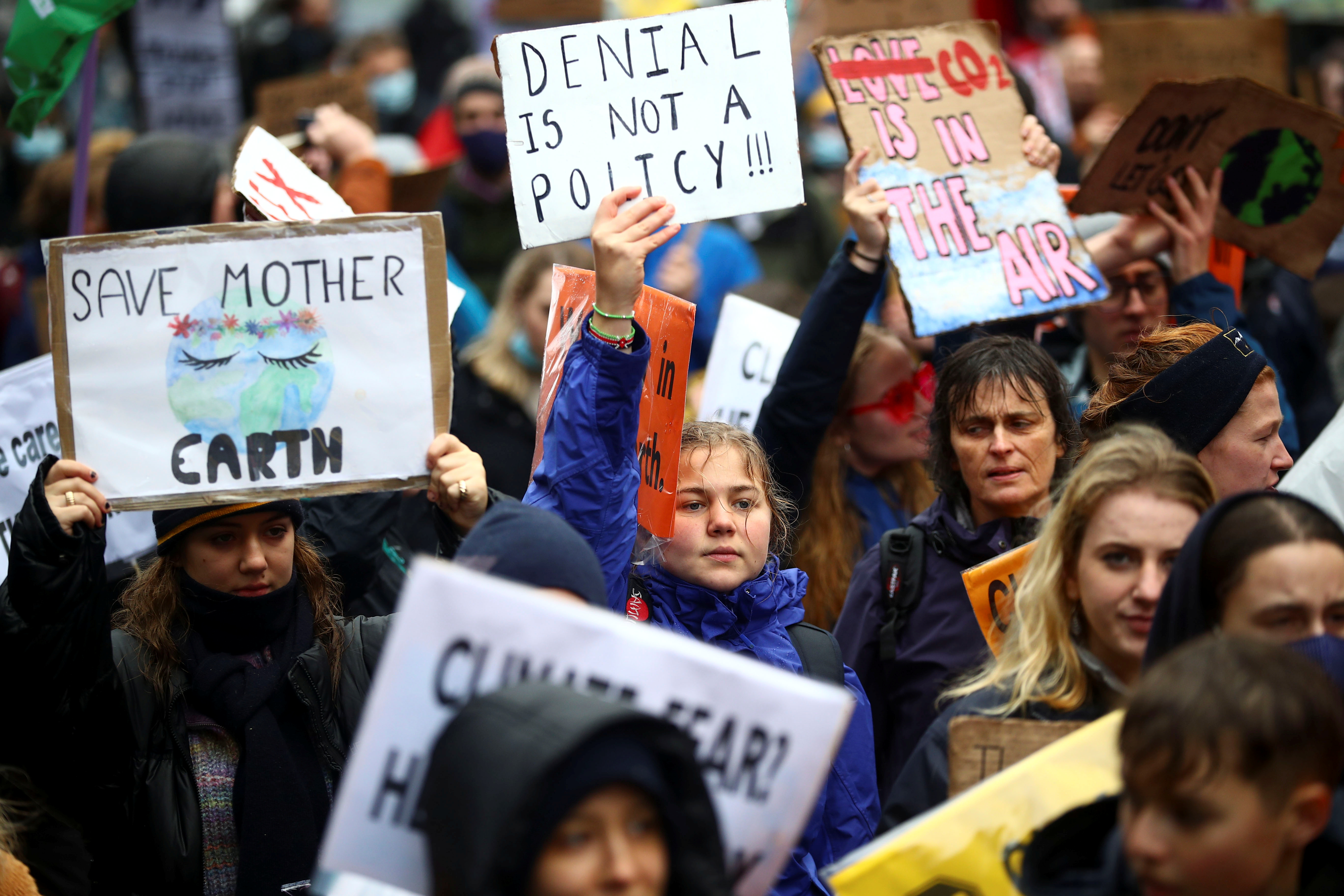 Demonstrators hold up signs during a protest as the UN Climate Change Conference (COP26) takes place, in Glasgow, Scotland on November 6, 2021 [Reuters/Hannah McKay]