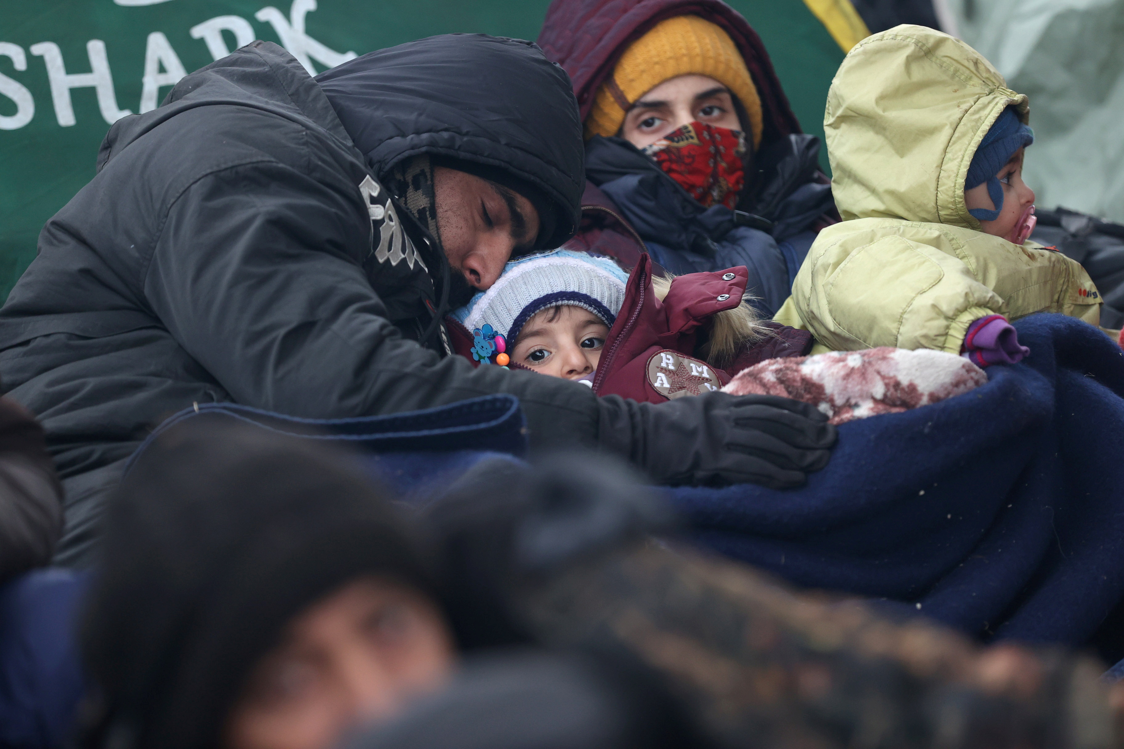 A family rests next to a tent set up on the Belarusian-Polish border at the Bruzgi-Kuznica Bialostocka border crossing in the Grodno Region, Belarus, on November 15, 2021