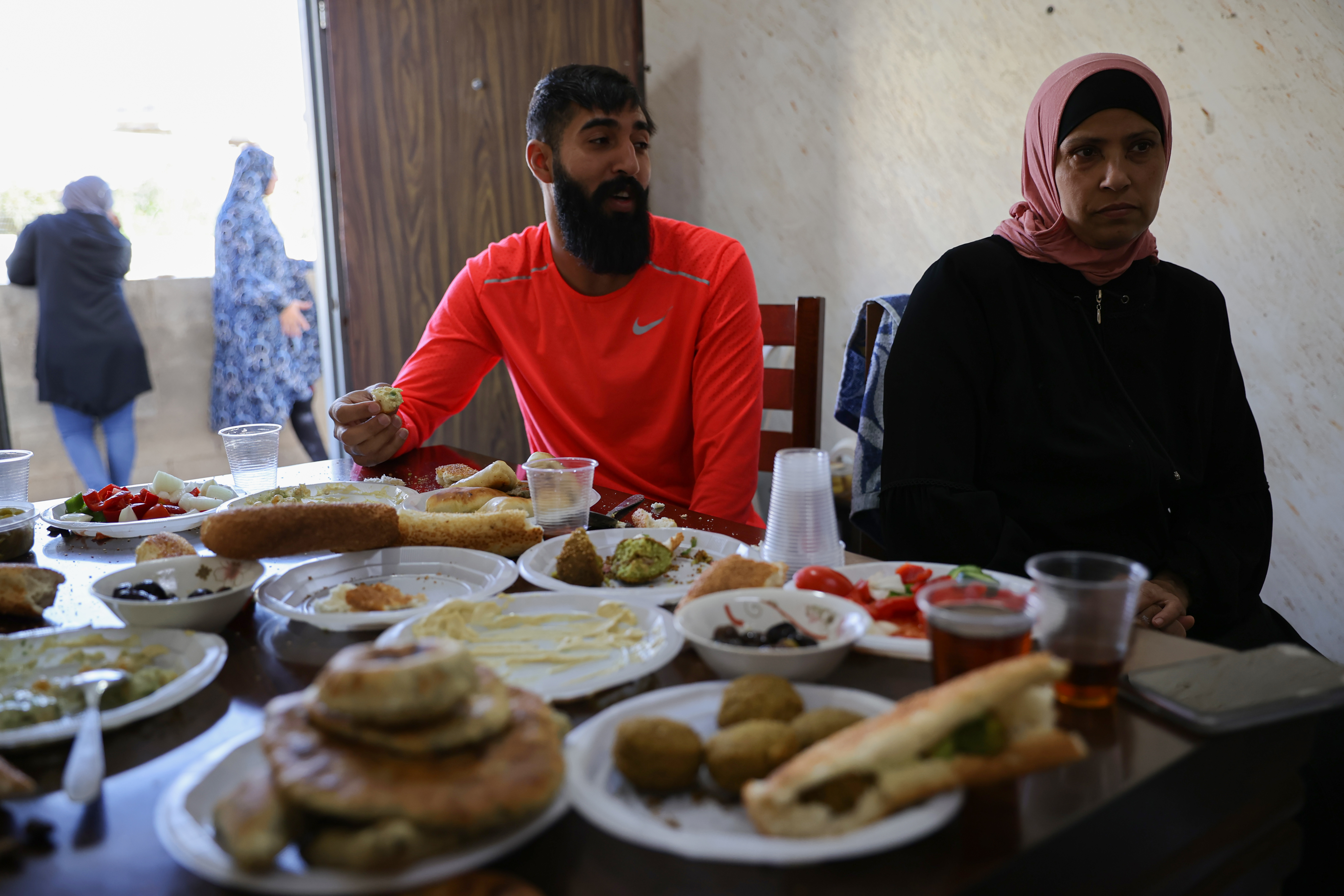 Iyad al-Ghouj sits beside his mother, Rania. The 11-member al-Ghouj family lives in a three-bedroom apartment [Al Jazeera]
