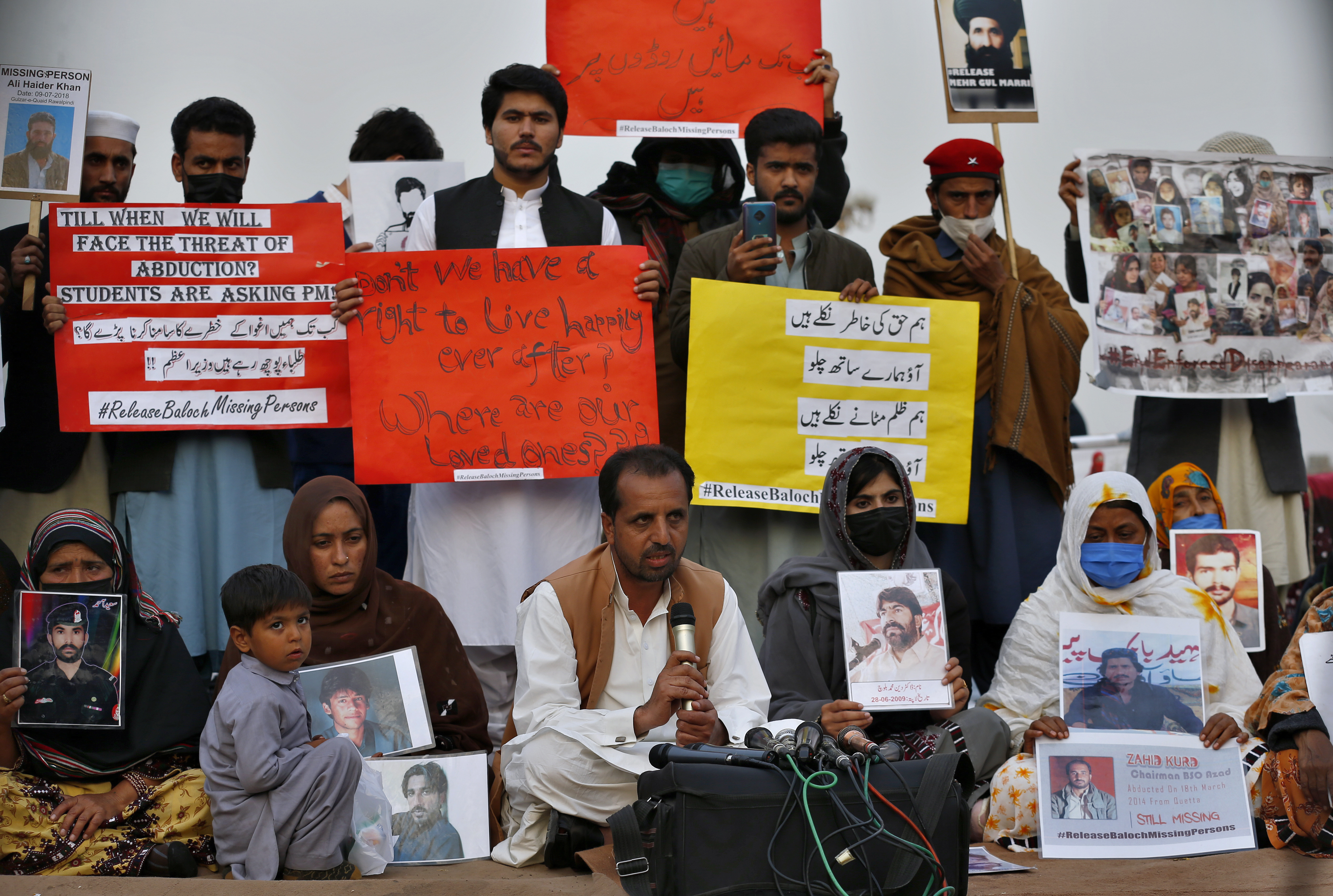 Nasrullah Baloch, centre bottom, leader of the Voice of Baloch Missing Persons, speaks while people hold placards and portraits of their missing family members during a news conference in Islamabad