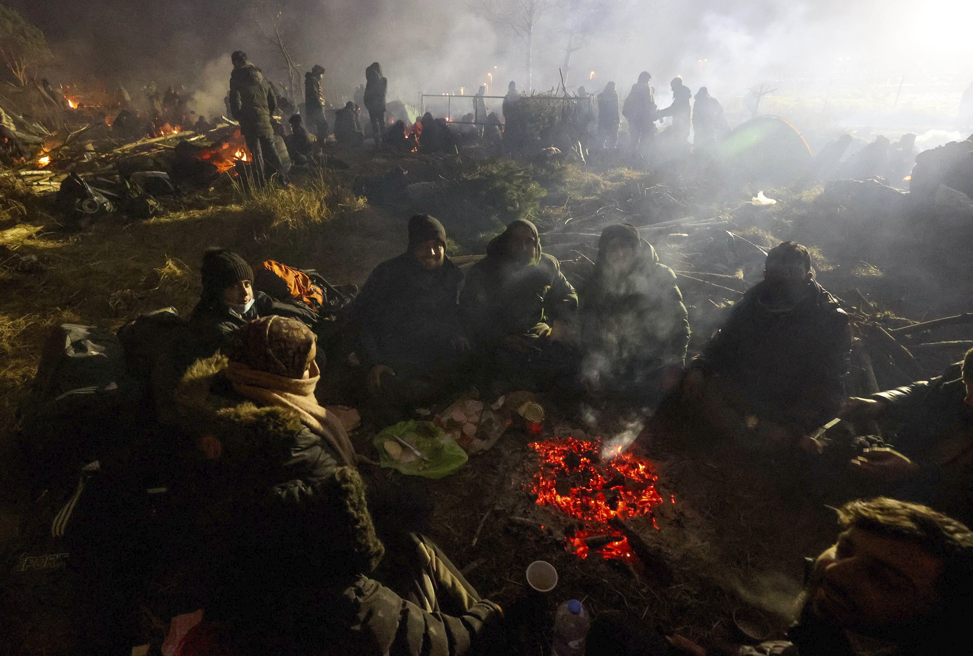 Migrants warm themselves near a fire at the checkpoint “Kuznitsa” at the Belarus-Poland border near Grodno, Belarus