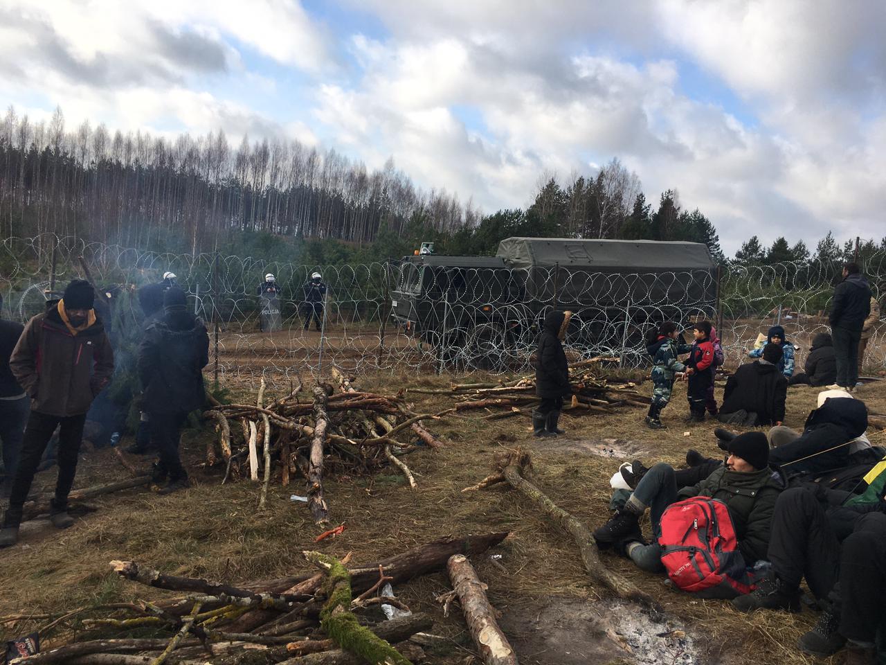 Migrants from the Middle East and elsewhere rest on the ground as they gather at the Belarus-Poland border [Al Jazeera]