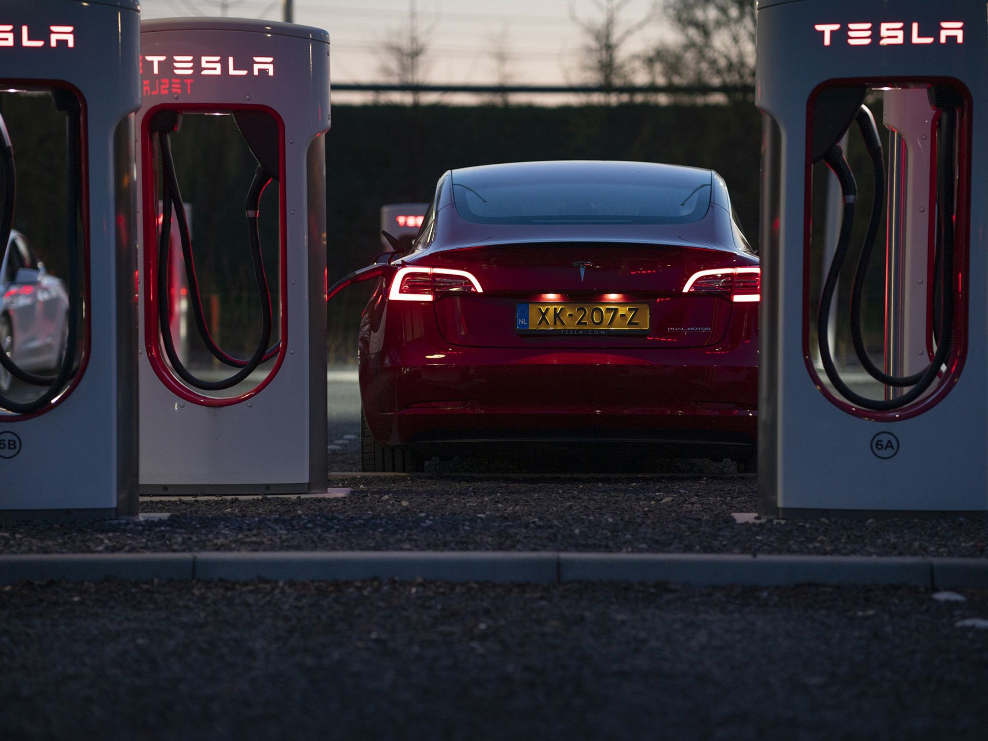 A Tesla Inc Model 3 electric automobile stands charging at dusk at a Tesla Supercharger station in Breukelen, the Netherlands