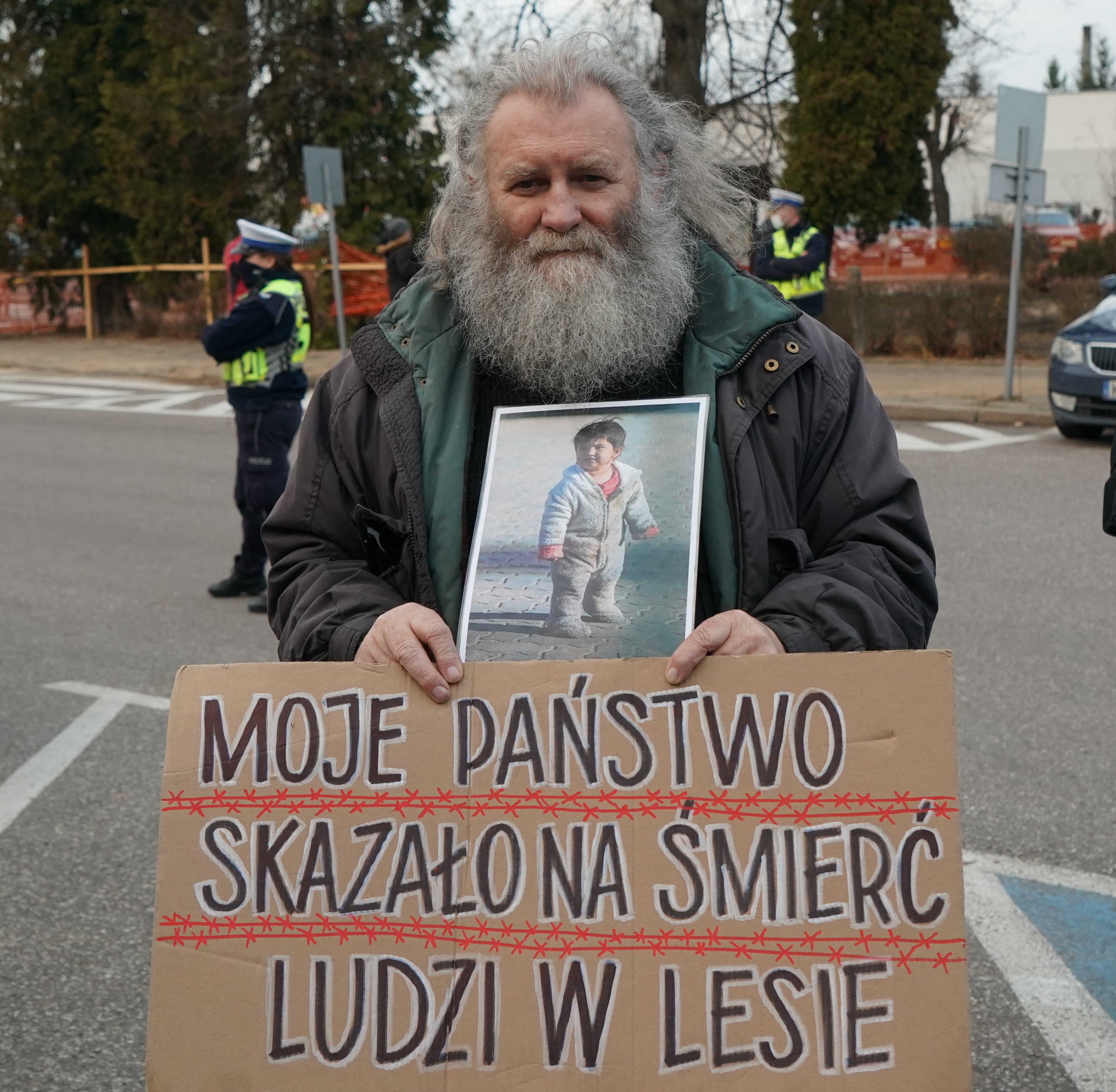 A man protests with a placard that reads ‘My country condemns people in the forest to death’ to draw attention to the humanitarian situation on the Polish-Belarusian border focusing on children, in Hajnowka, near the border on November 20, 2021