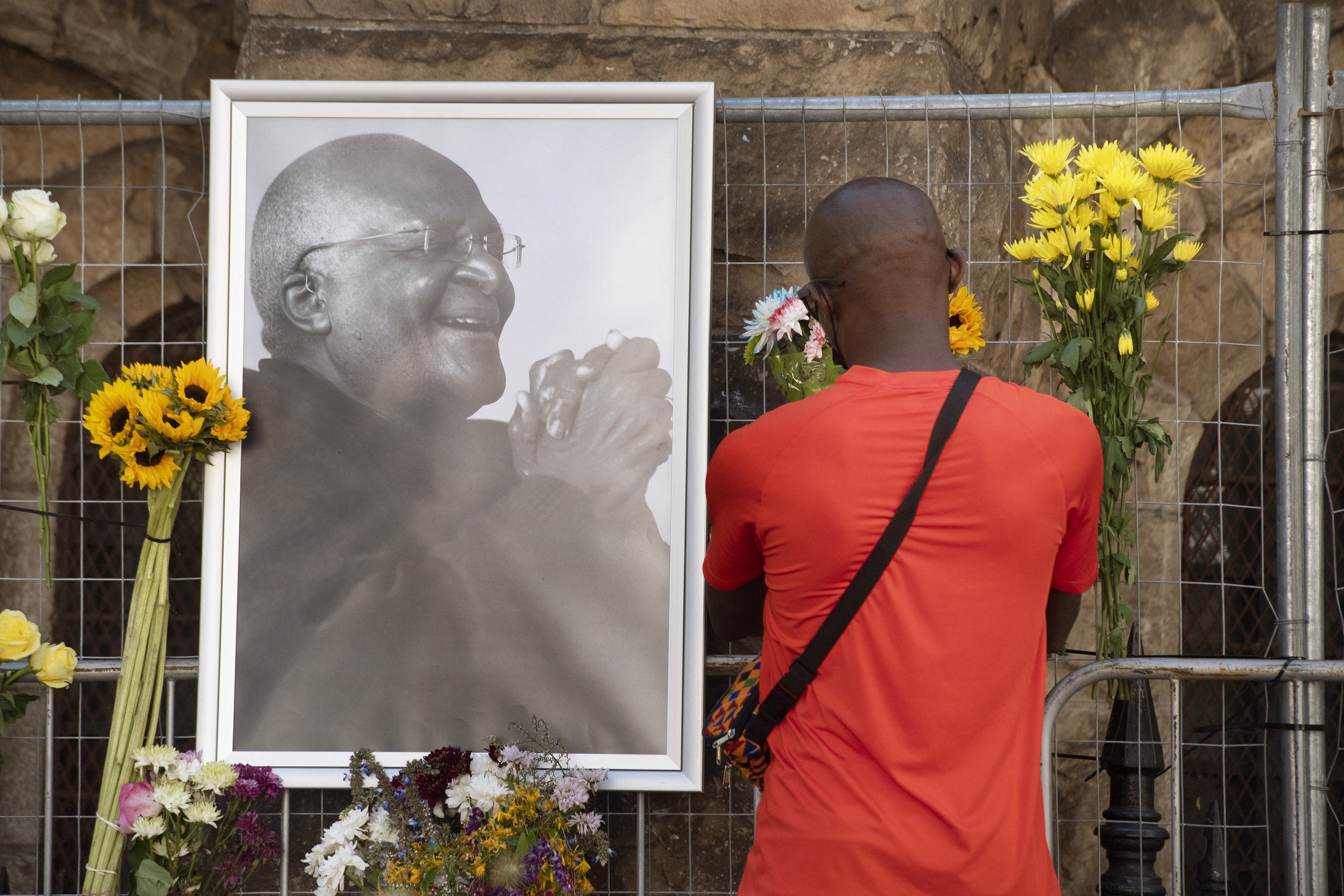 A mourner brings flowers to a Wall of Remembrance for Archbishop Tutu that has been set up at St George’s