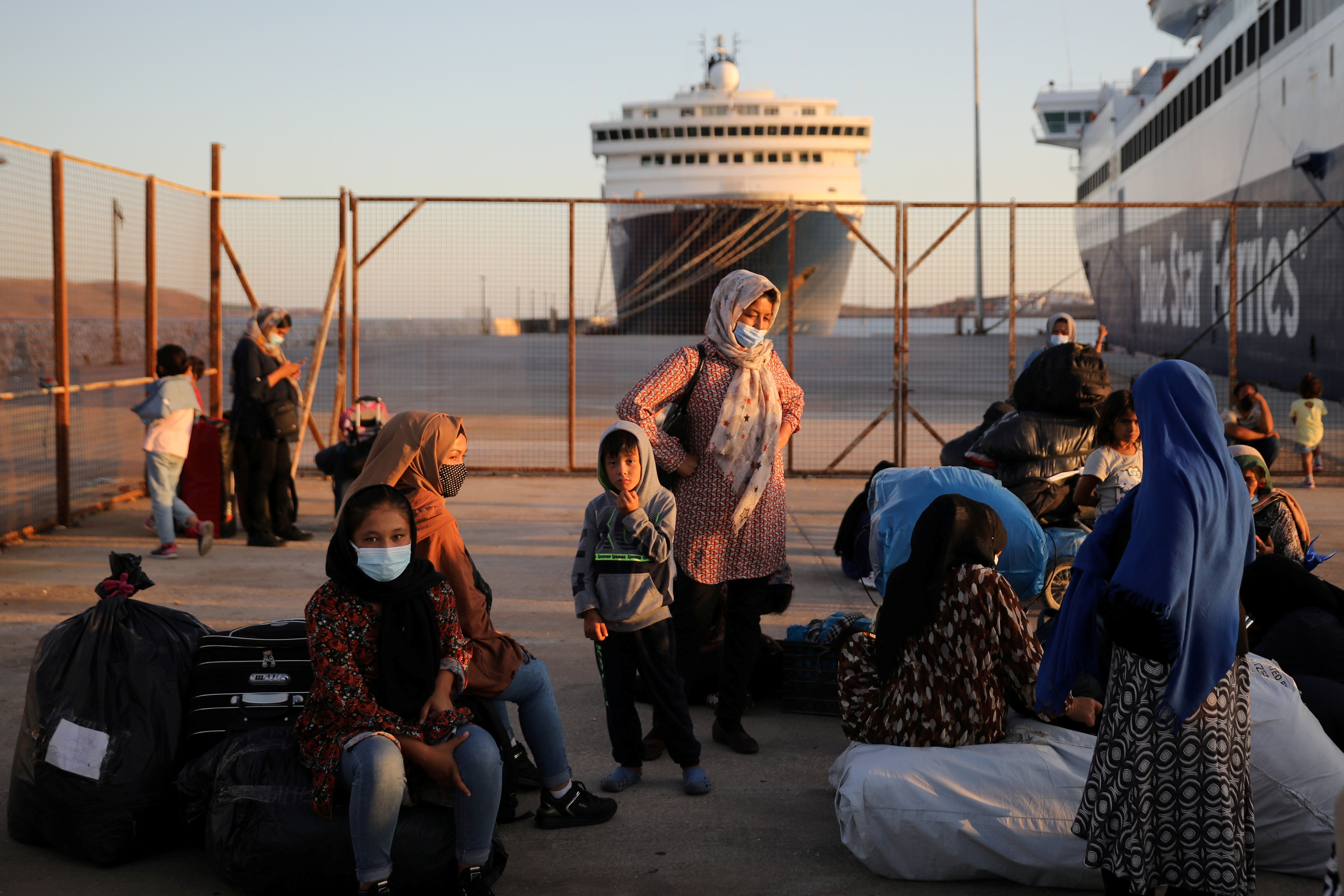 Refugees and migrants wait to be transferred to camps on the mainland after their arrival on a passenger ferry from the island of Lesbos at the port of Lavrio, Greece