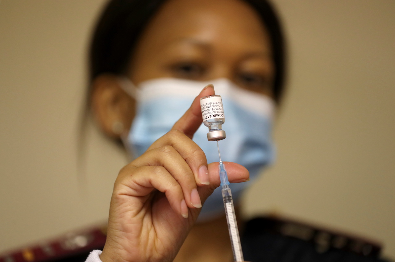 A health worker holds a vial of the Pfizer-BioNTech COVID-19 vaccine