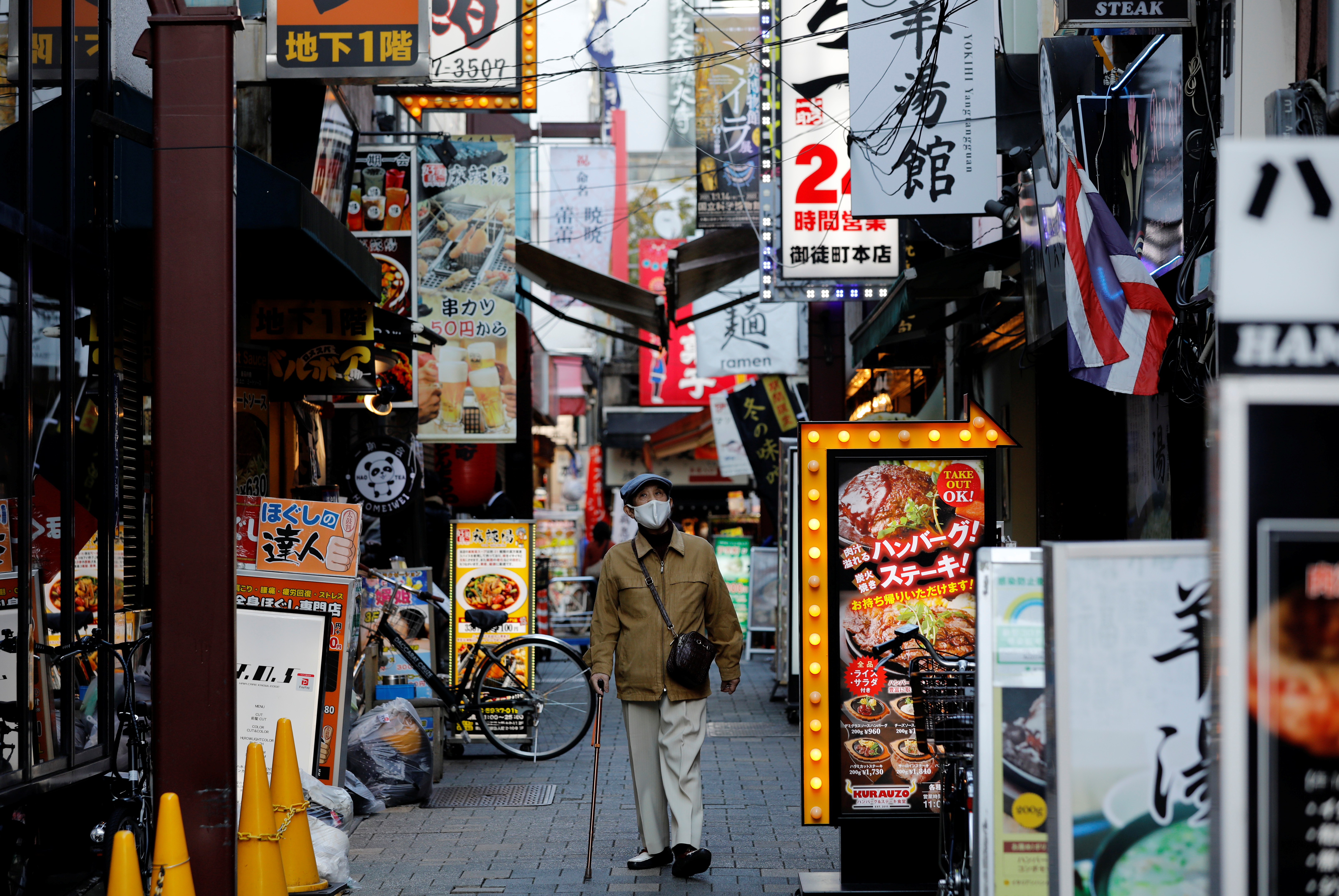 A man wearing a protective mask, amid the coronavirus disease (COVID-19) outbreak, makes his way at a restaurant district in Tokyo, Japan