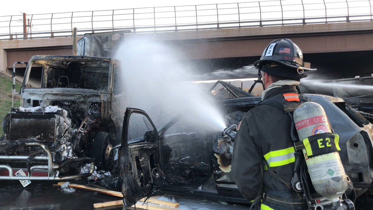 A fireman sprays water on the charred remains of cars and trucks