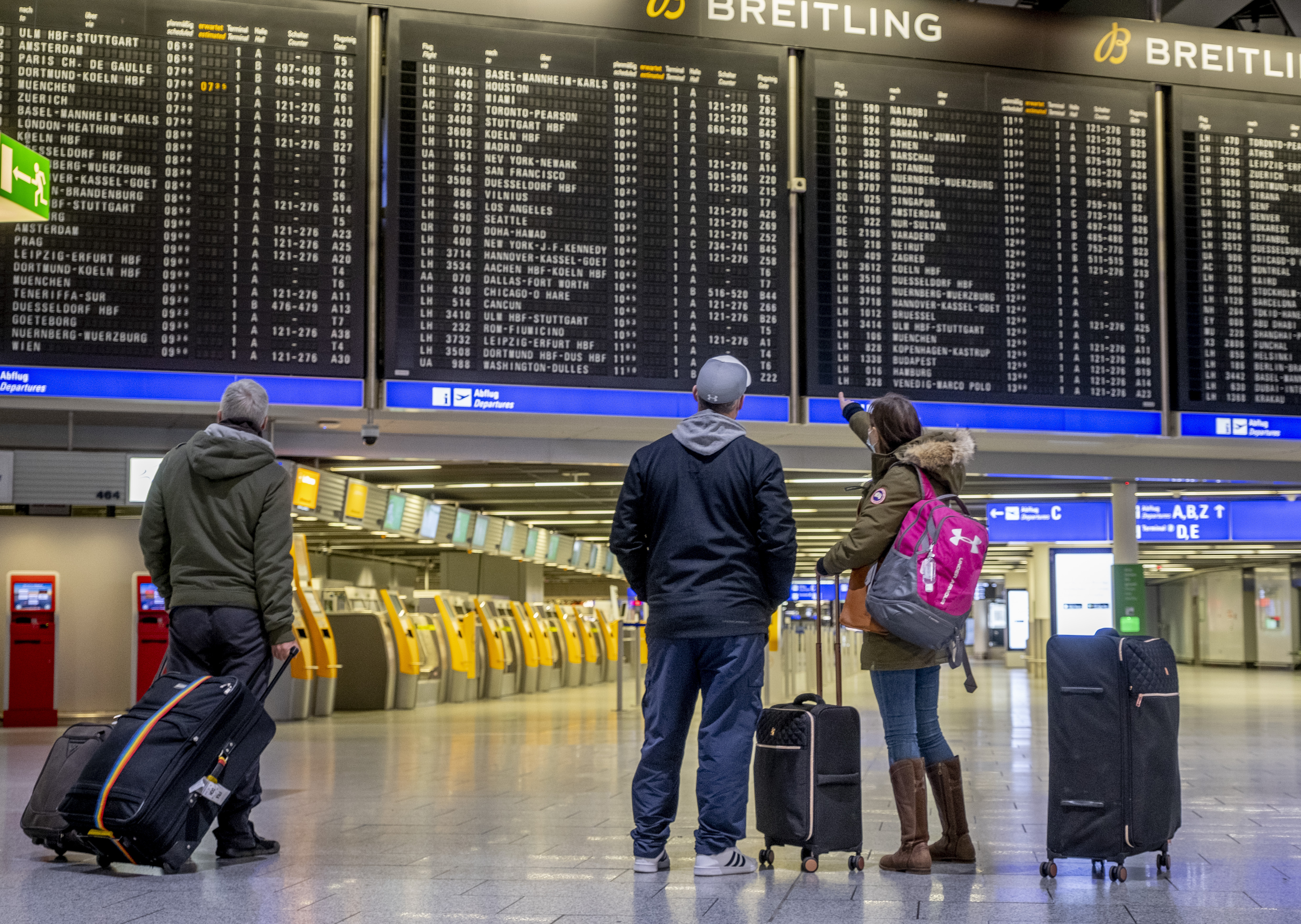 Passengers check the flight board in a terminal at the international airport in Frankfurt