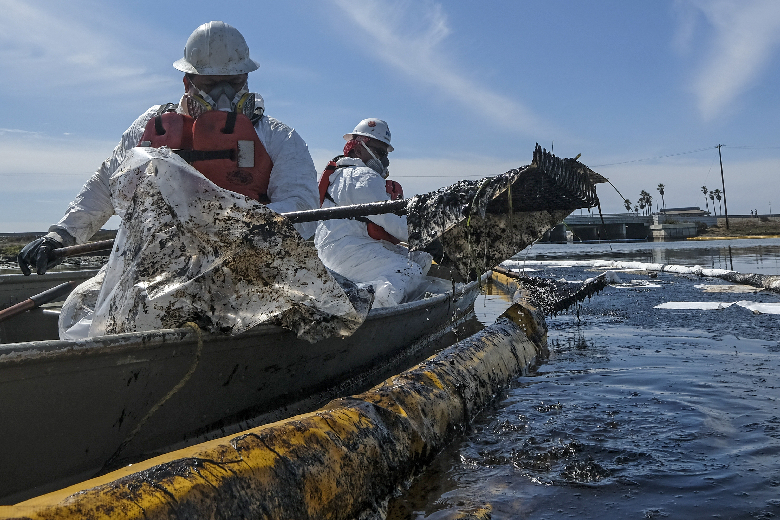 Cleanup contractors deploy skimmers and floating barriers known as booms to try to stop further crude oil incursion into the Wetlands Talbert Marsh in Huntington Beach
