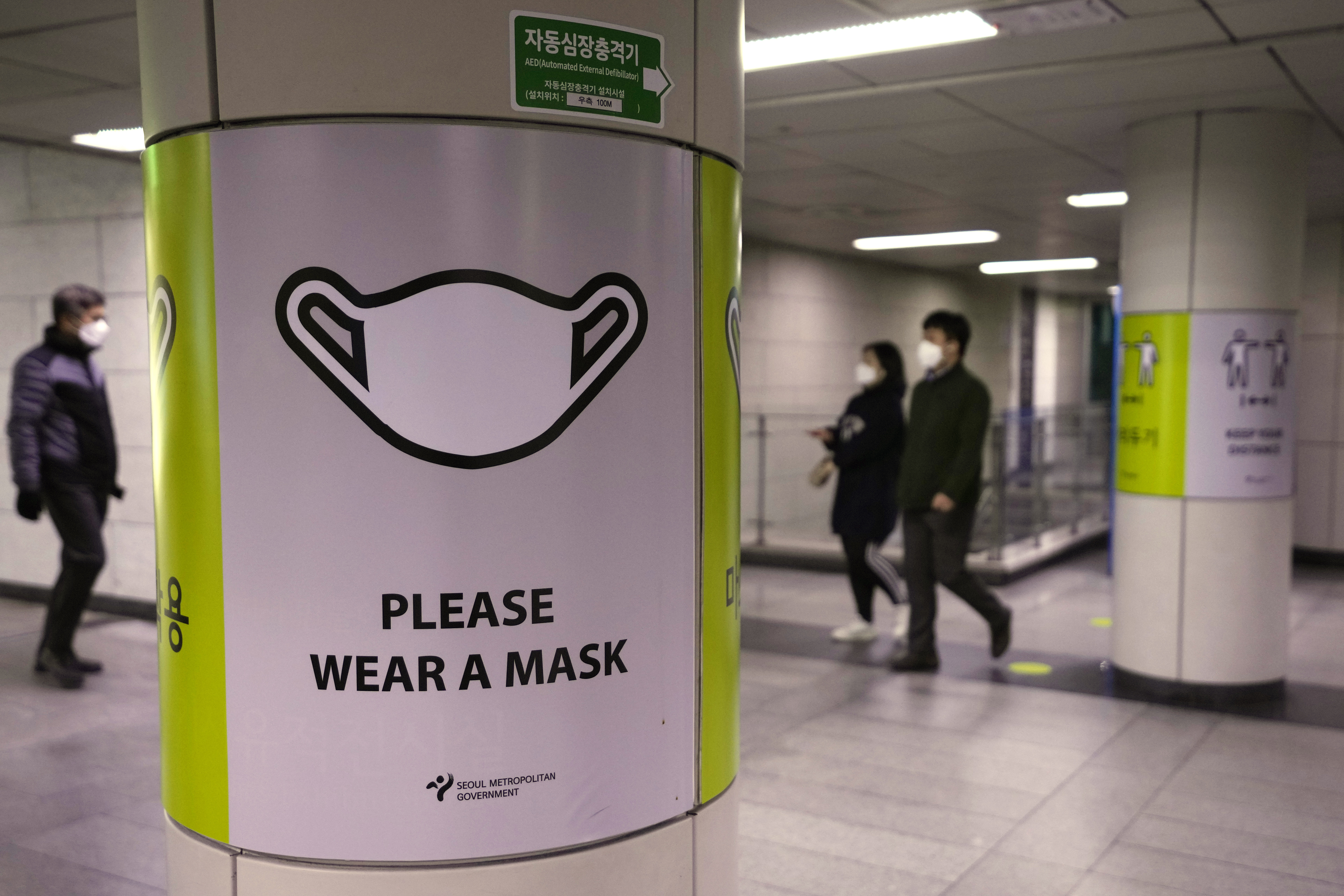 People wearing face masks pass by posters reminding precautions against the coronavirus at a subway station in Seoul, South Korea