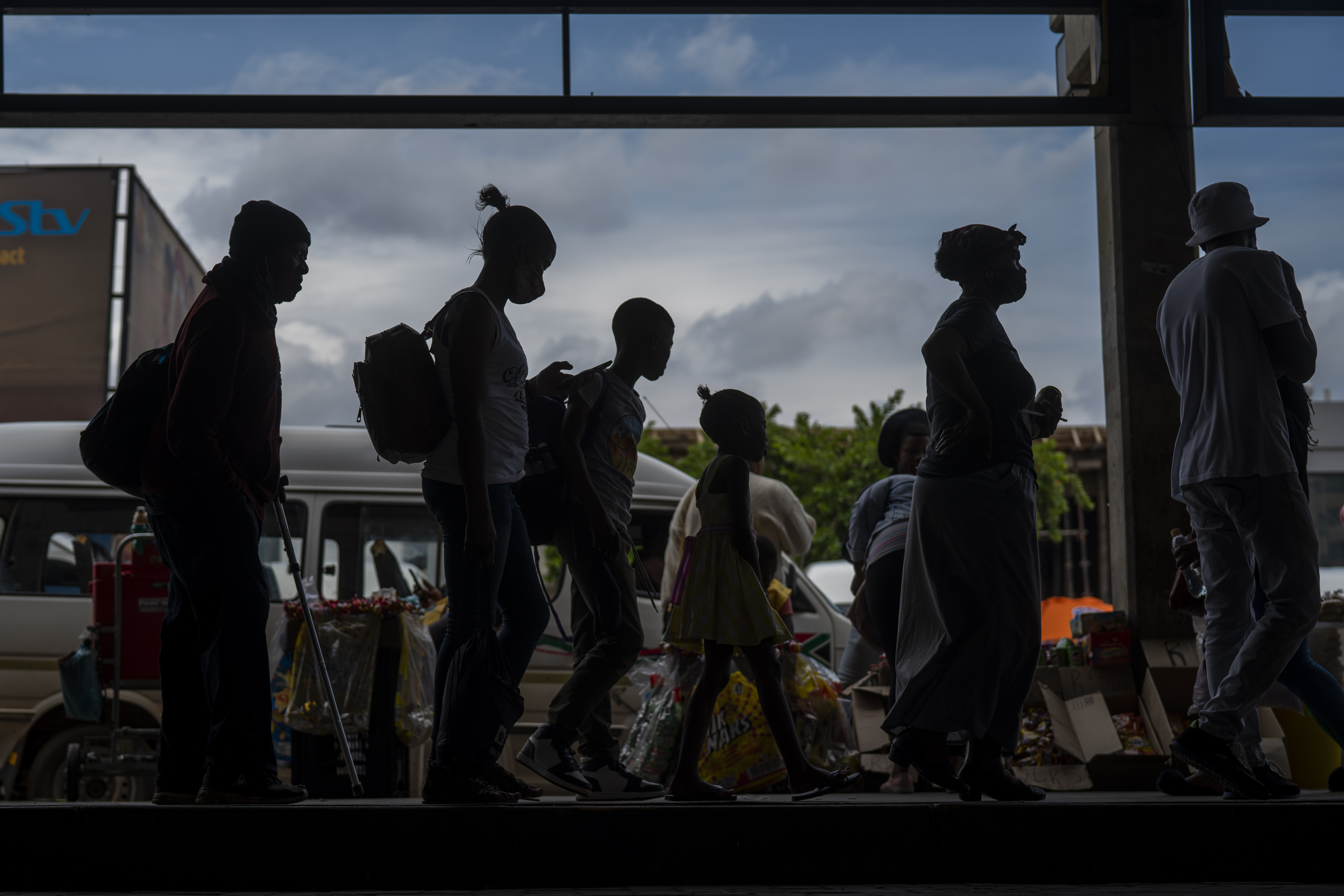 Passengers, some wearing masks, line up to board a taxi at the Baragwanath taxi rank in Soweto, South Africa