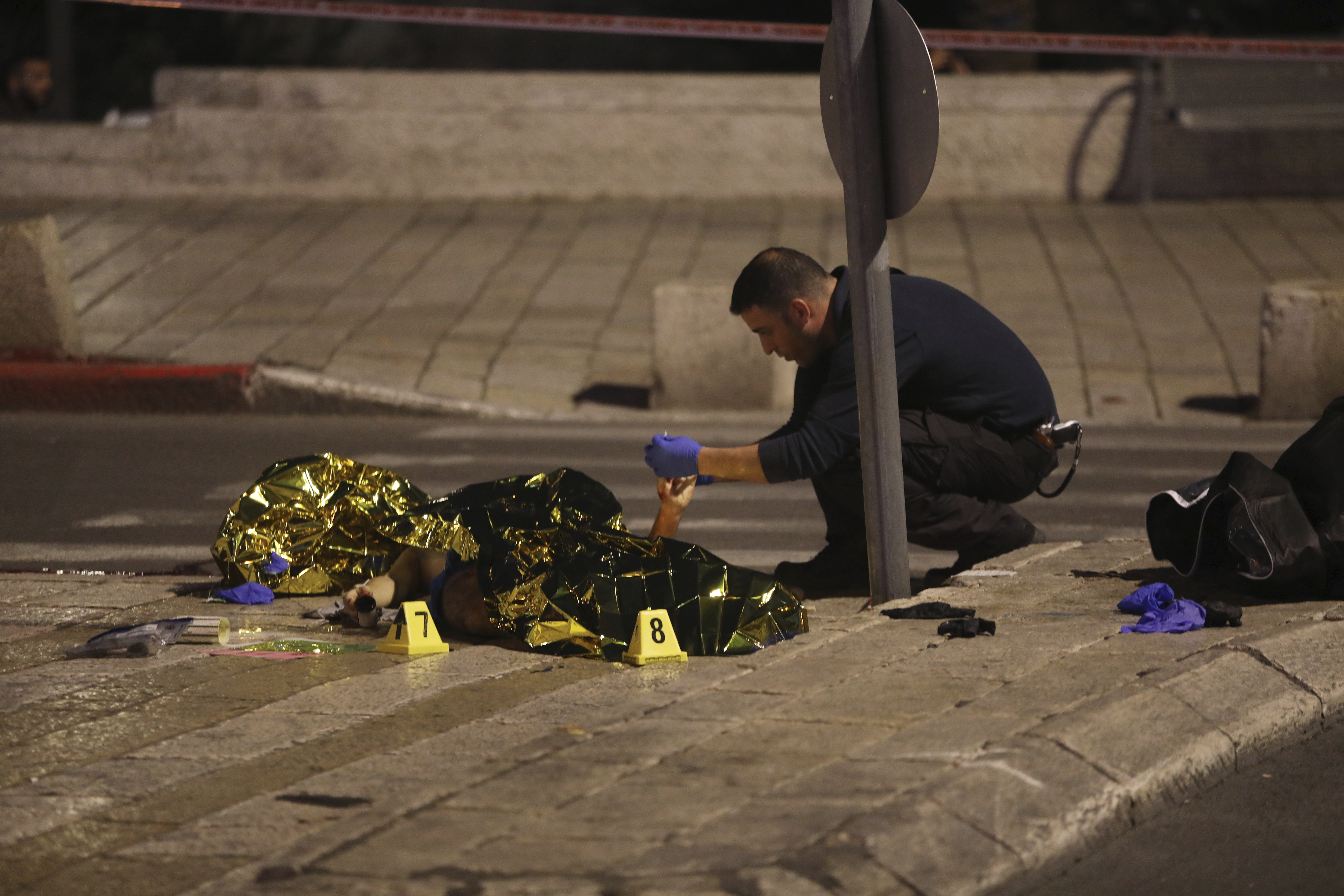 An Israeli policeman examines the body of a man shot near the Old City of Jerusalem