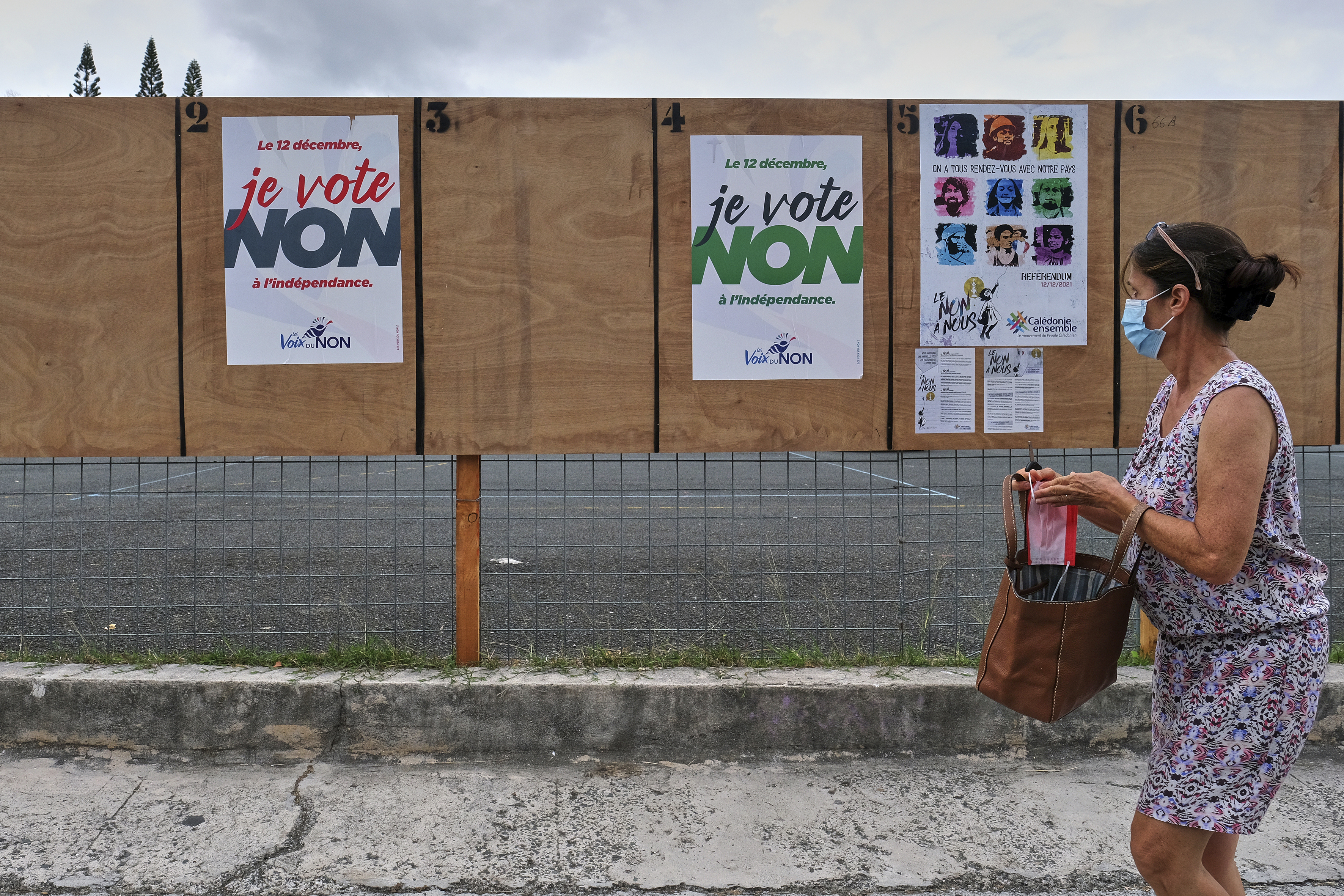 A woman walks past electoral posters calling to vote’ No’ to the referendum in Noumea, New Caledonia