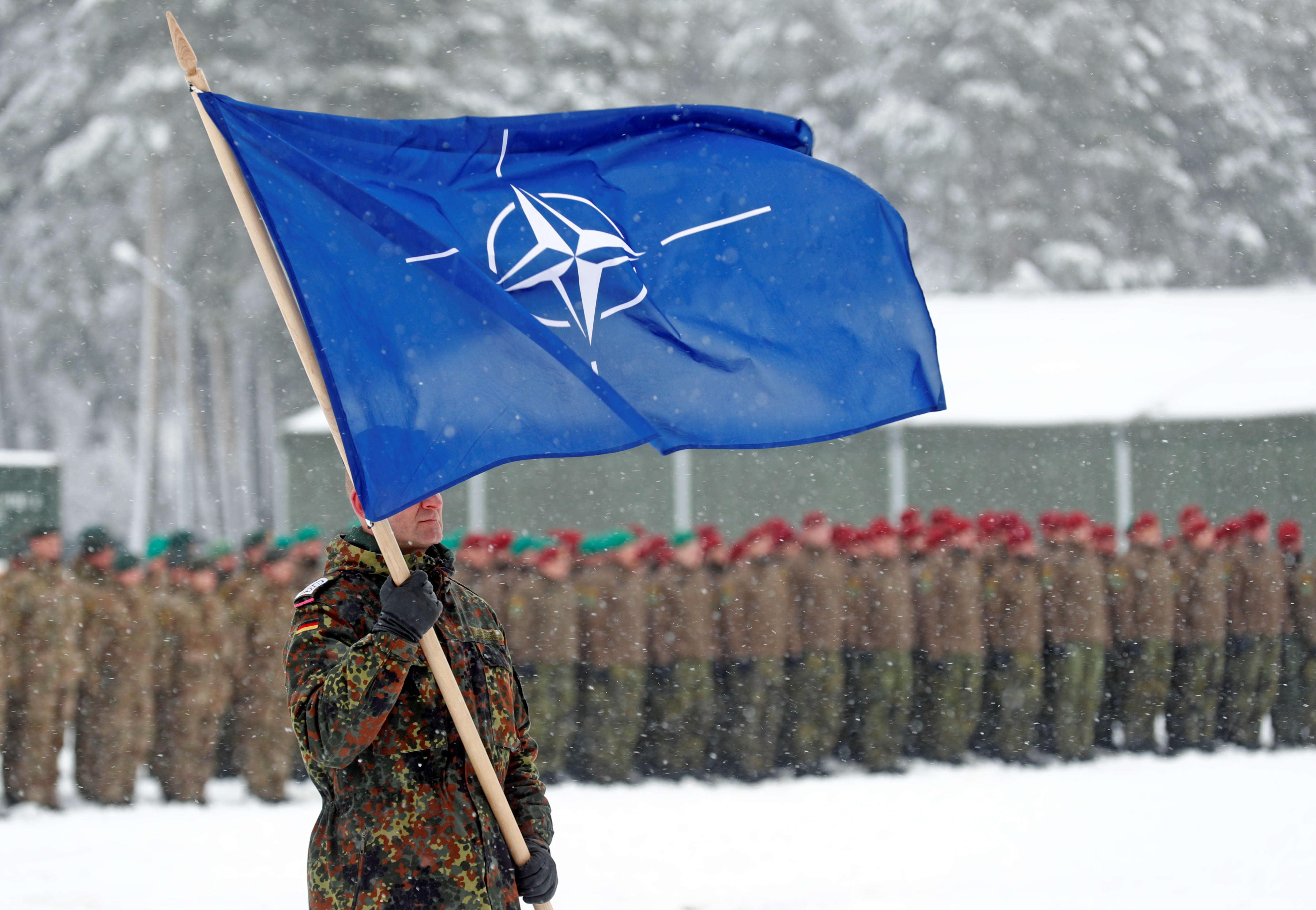 A soldier carries the NATO flag