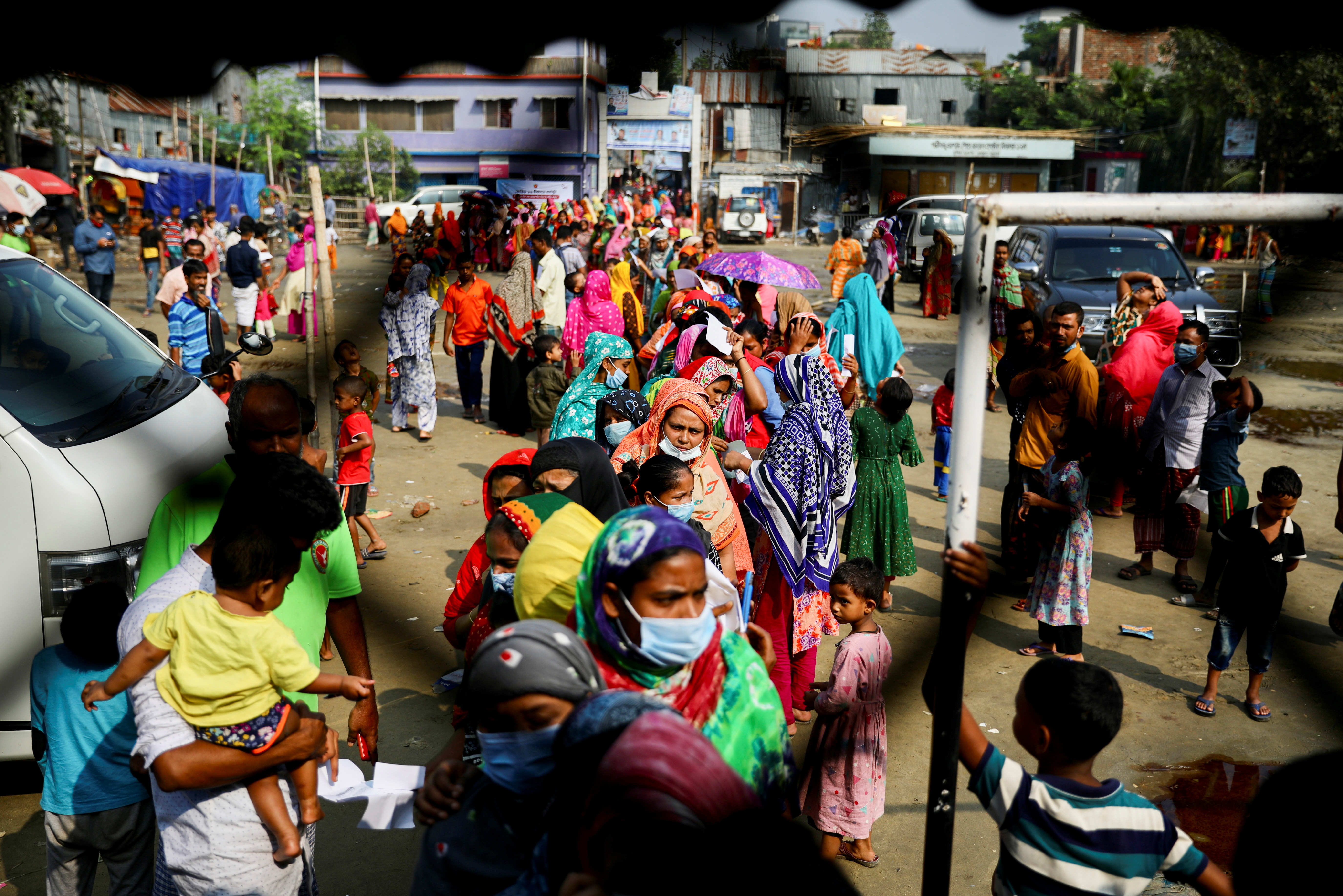 Slum-dwellers stand in a queue to get vaccines in Korail Slum in Dhaka