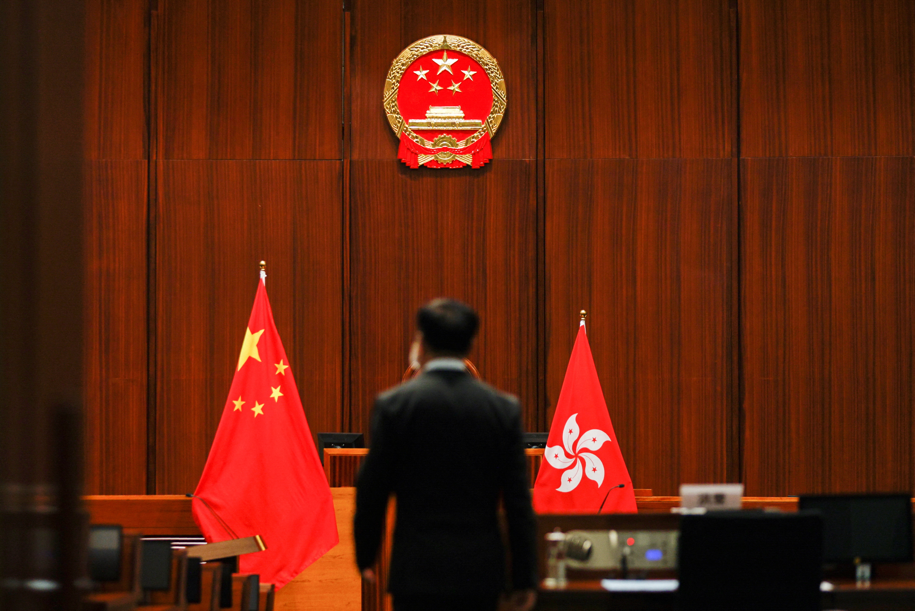 A security guard stands below the Chinese national emblem before newly-elected legislators take their oath at the Legislative Council in Hong Kong on Monday