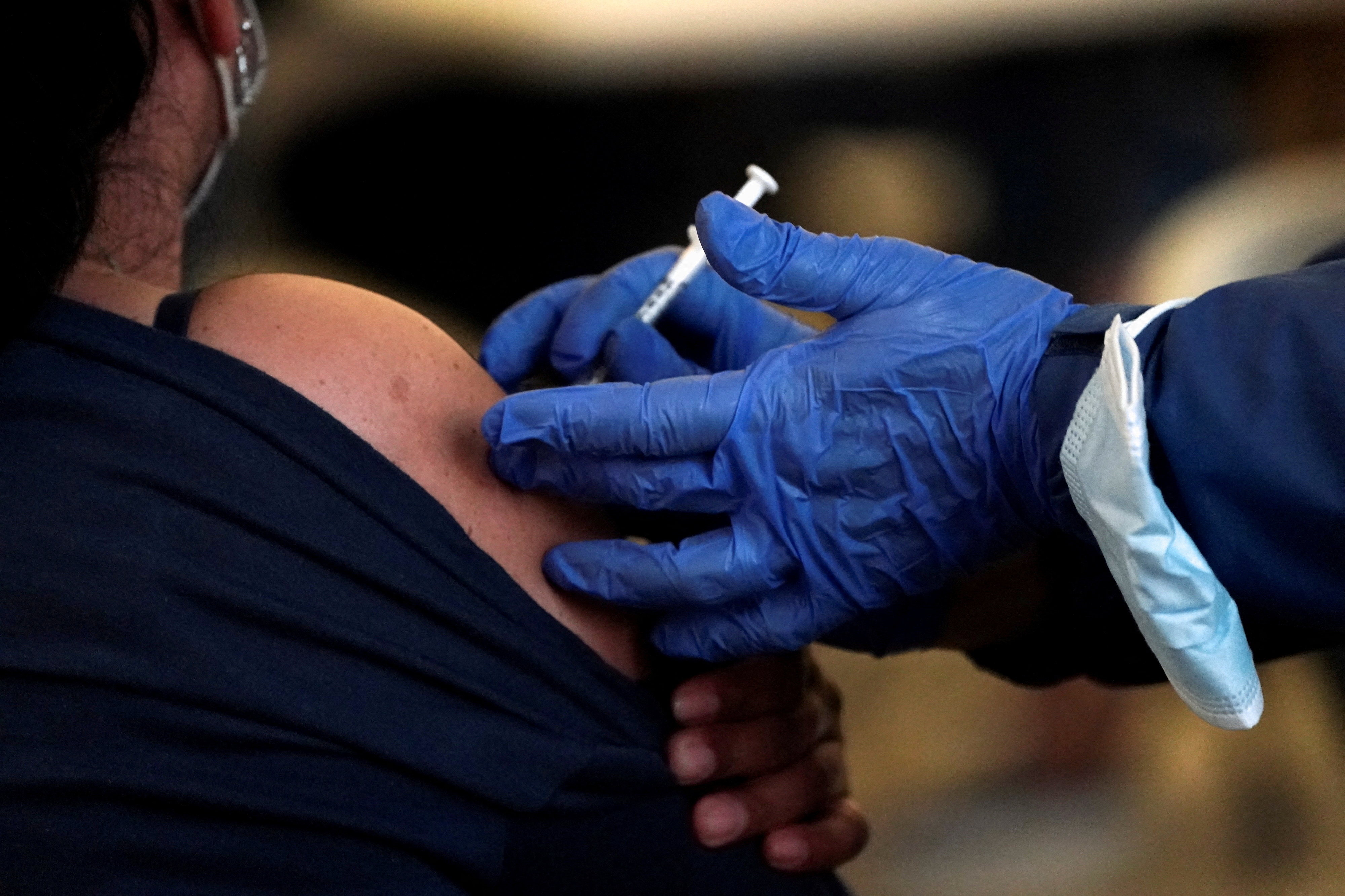 A health worker administers a COVID jab in a woman's shoulder