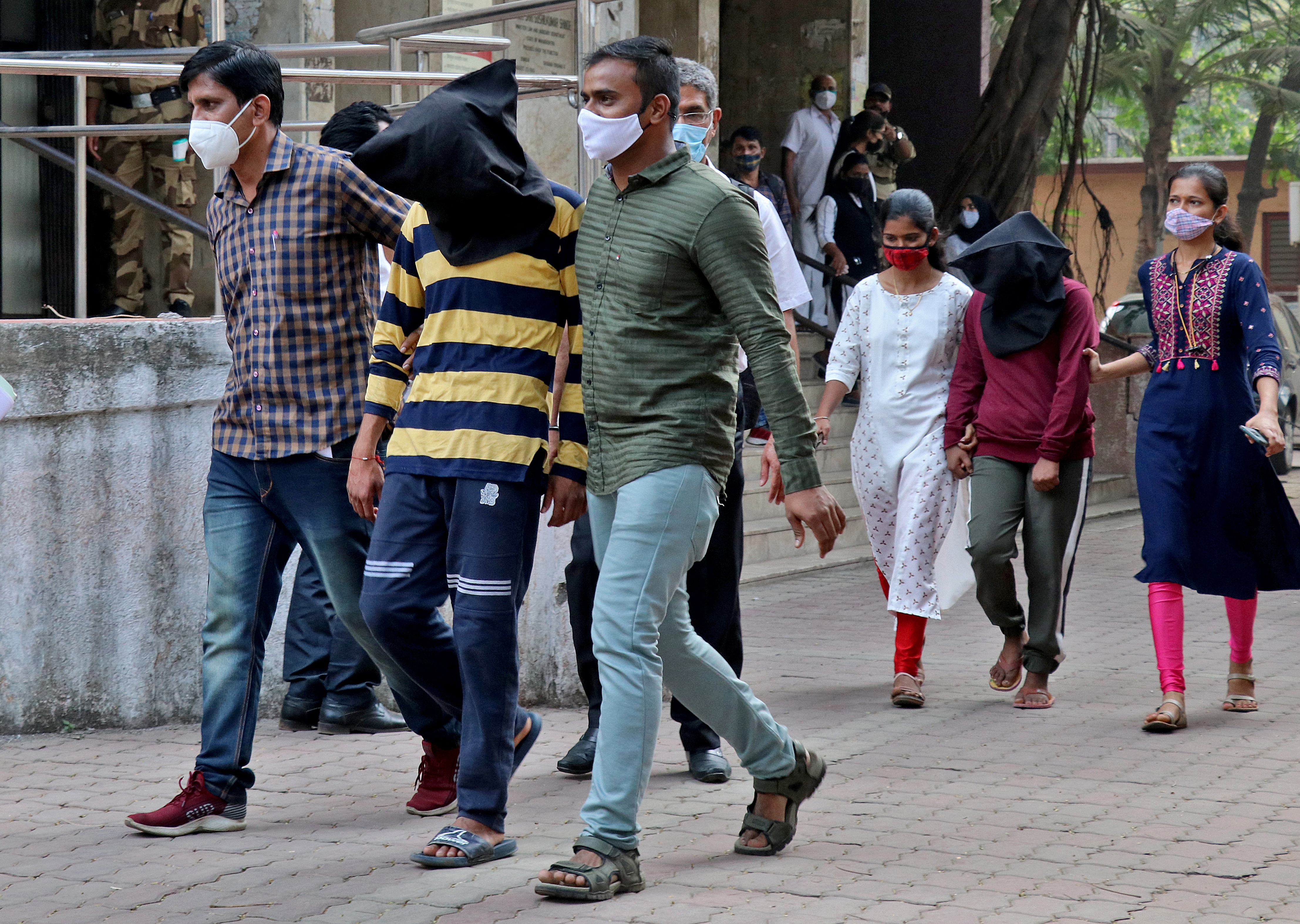 Police officials escort a man and a woman after they appeared before a court in Mumbai following their arrest over alleged involvement in Bulli Bai app