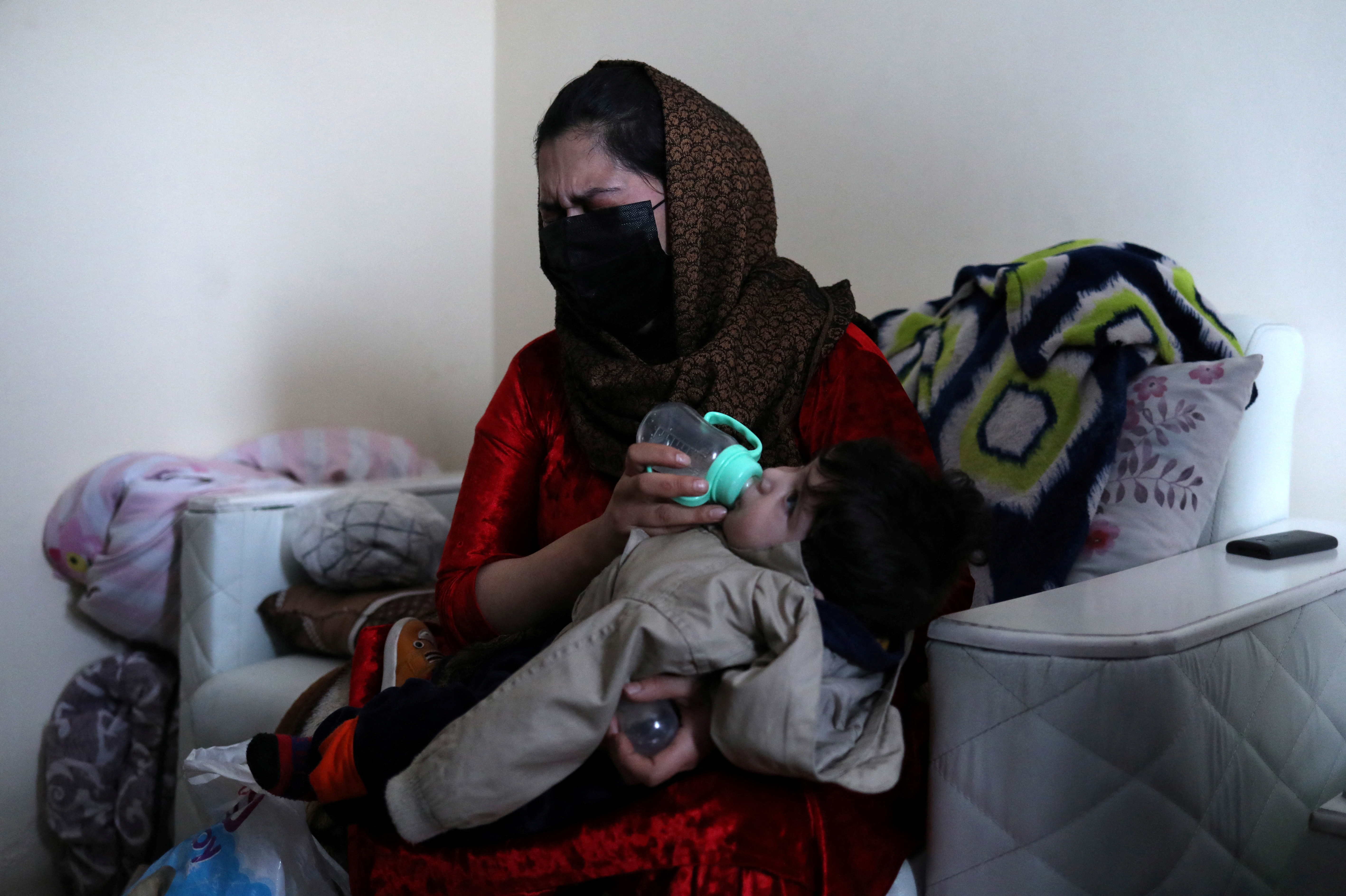 Farima Safi, wife of Hamid Safi, a taxi driver who had found baby Sohail Ahmadi in the airport, weeps as she feeds Sohail at her house in Kabul