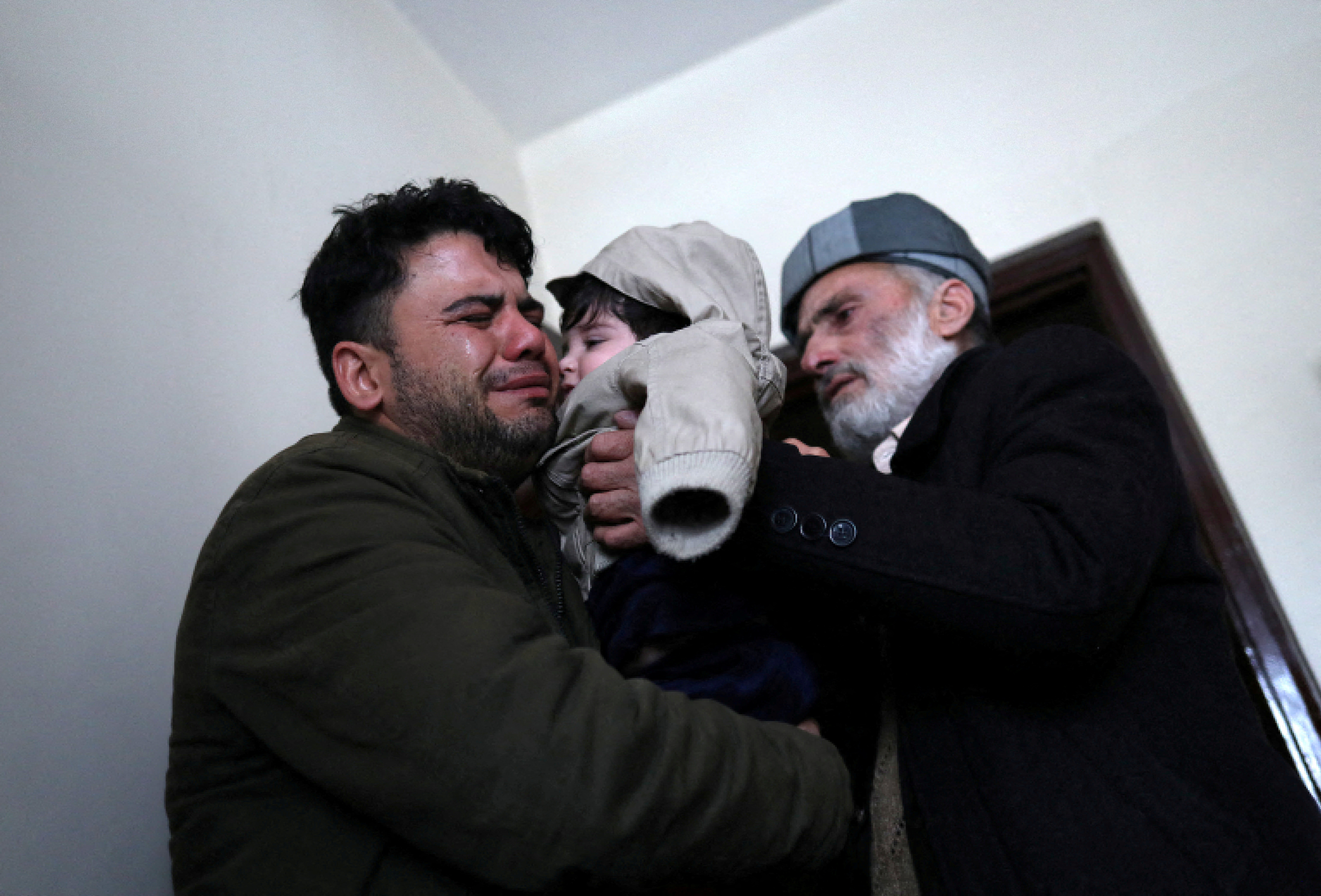 Hamid Safi, a 29-year-old taxi driver who had found baby Sohail Ahmadi in the airport, cries as he hands over Sohail to his grandfather Mohammad Qasem Razawi in Kabul